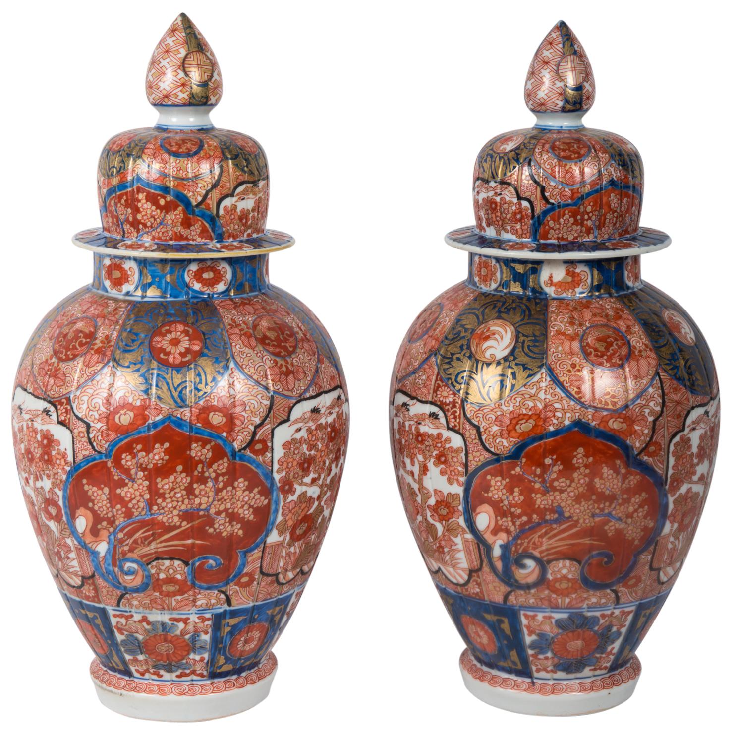 A fine quality pair of late 19th century Japanese Imari lidded vases, each with classical motif, floral and foliate decoration in the typical red and blue ground colors.