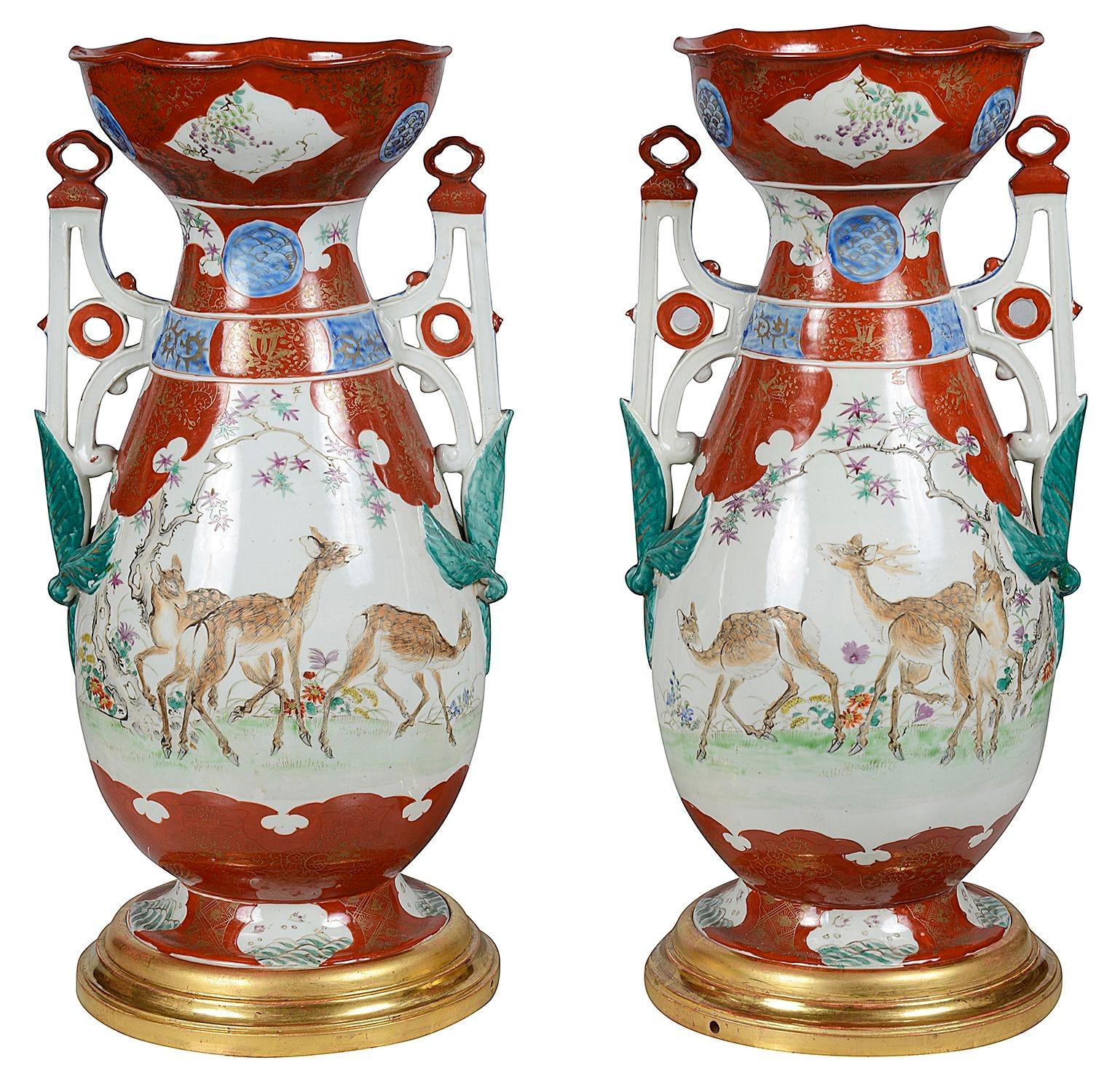 Une paire impressionnante et décorative de lampes en porcelaine japonaise Kutani du 19ème siècle. Chacun avec un fond orange, des poignées percées de chaque côté. Scènes de cerfs se nourrissant dans les bois, montées sur des socles en bois