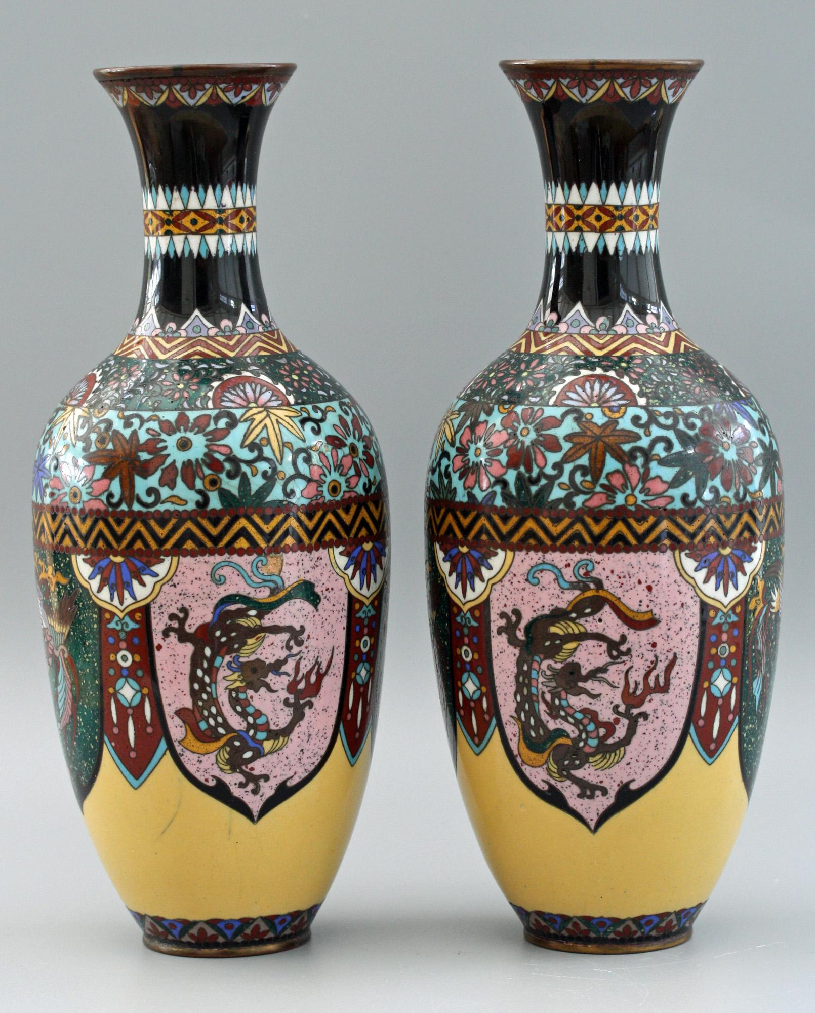 A very decorative pair antique Japanese Meiji period Rooster and Dragon panel cloisonné vases dating from the latter 19th or early 20th century. These striking vases stand on a narrow rounded foot with rounded baluster shaped bodies and narrow