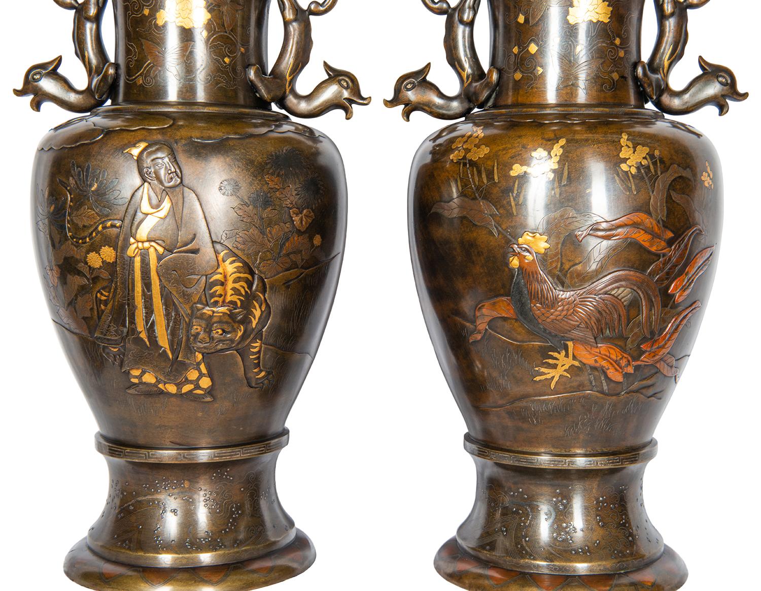 A fine quality pair of late 19th century, Meiji period (1868-1912) Miyao style patinated and engraved bronze vases with mythical dolphin like handles either side. Each with scenes of cockerels among foliage, one with a scholar walking through the