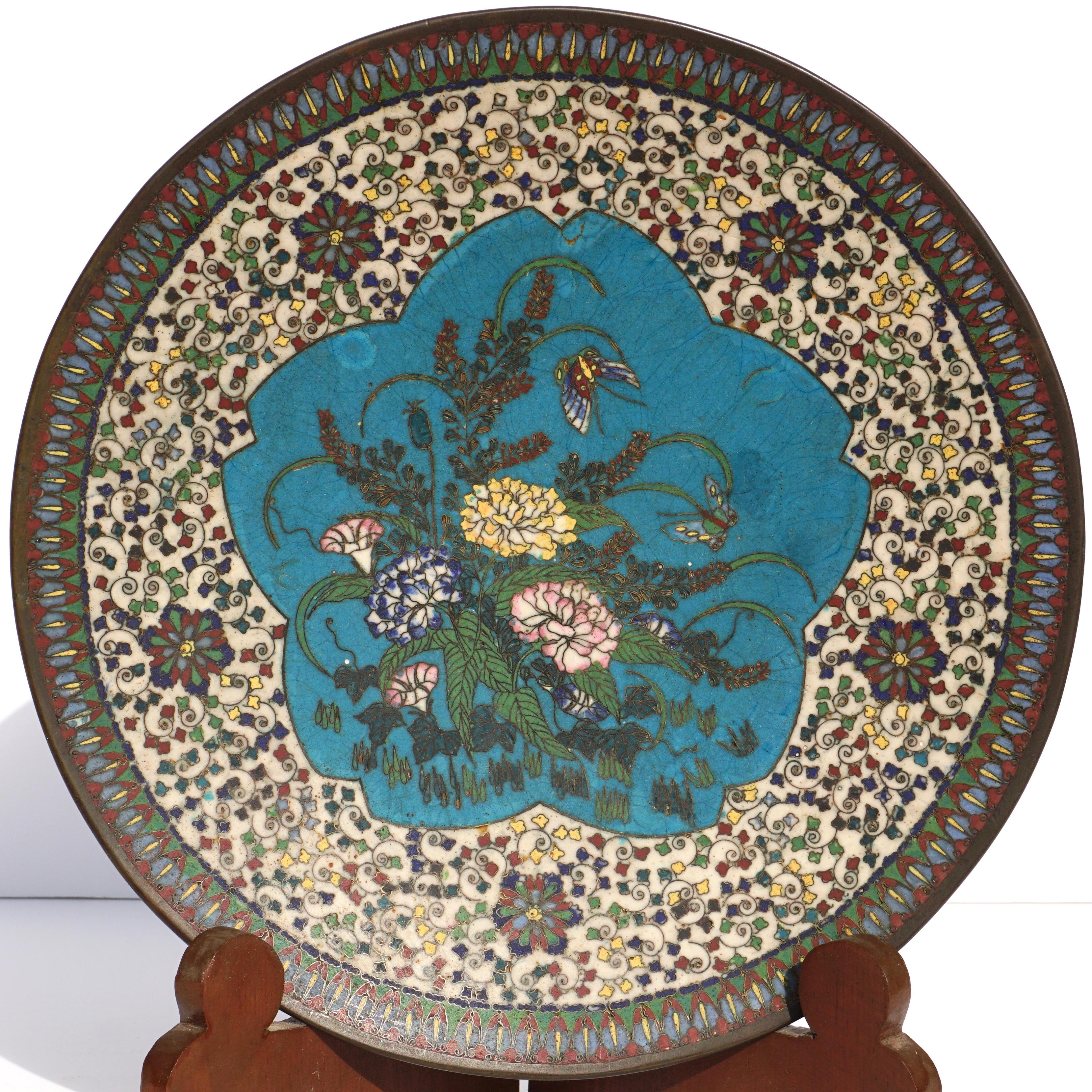 A rare and beautiful pair of charger plates from 1900 Meiji, Japan. Infused with fine and detailed enamel cloisonné work comprised of geometric and classical floral designs. Add some birds, butterflies and insects and these chargers are ready to add