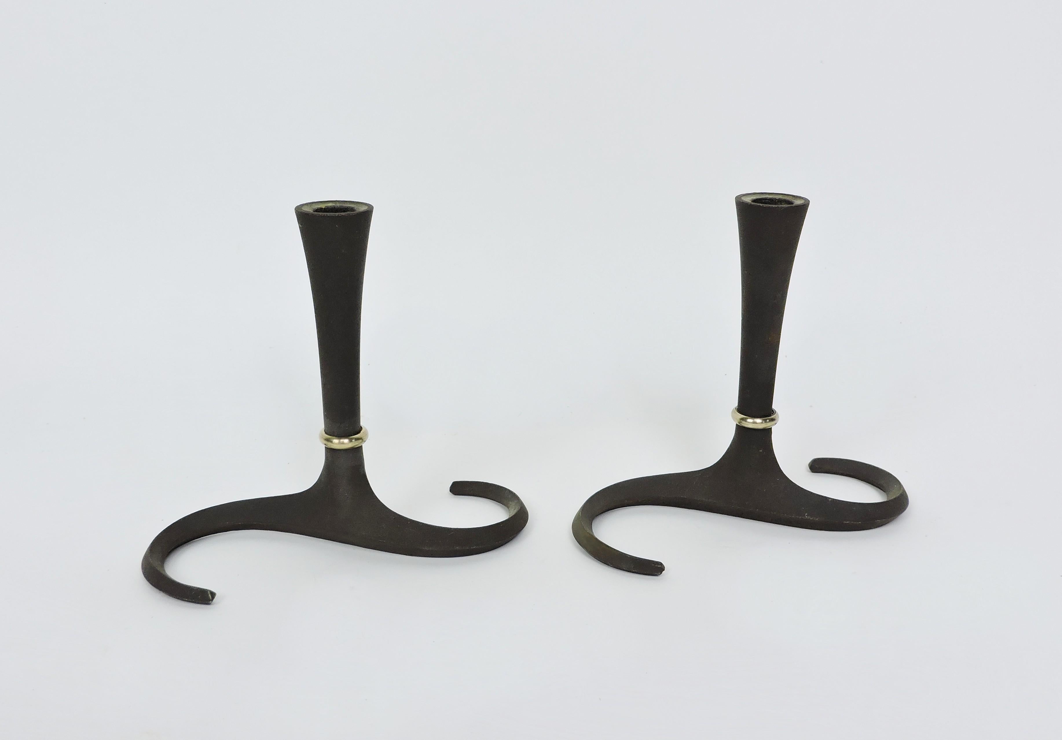 Beautiful and elegant pair of early cast iron candle holders with brass accents designed by Jens Quistgaard and made in Denmark by Dansk. These candle holders have an S shaped base that supports a gracefully tapered top and have a black matte finish