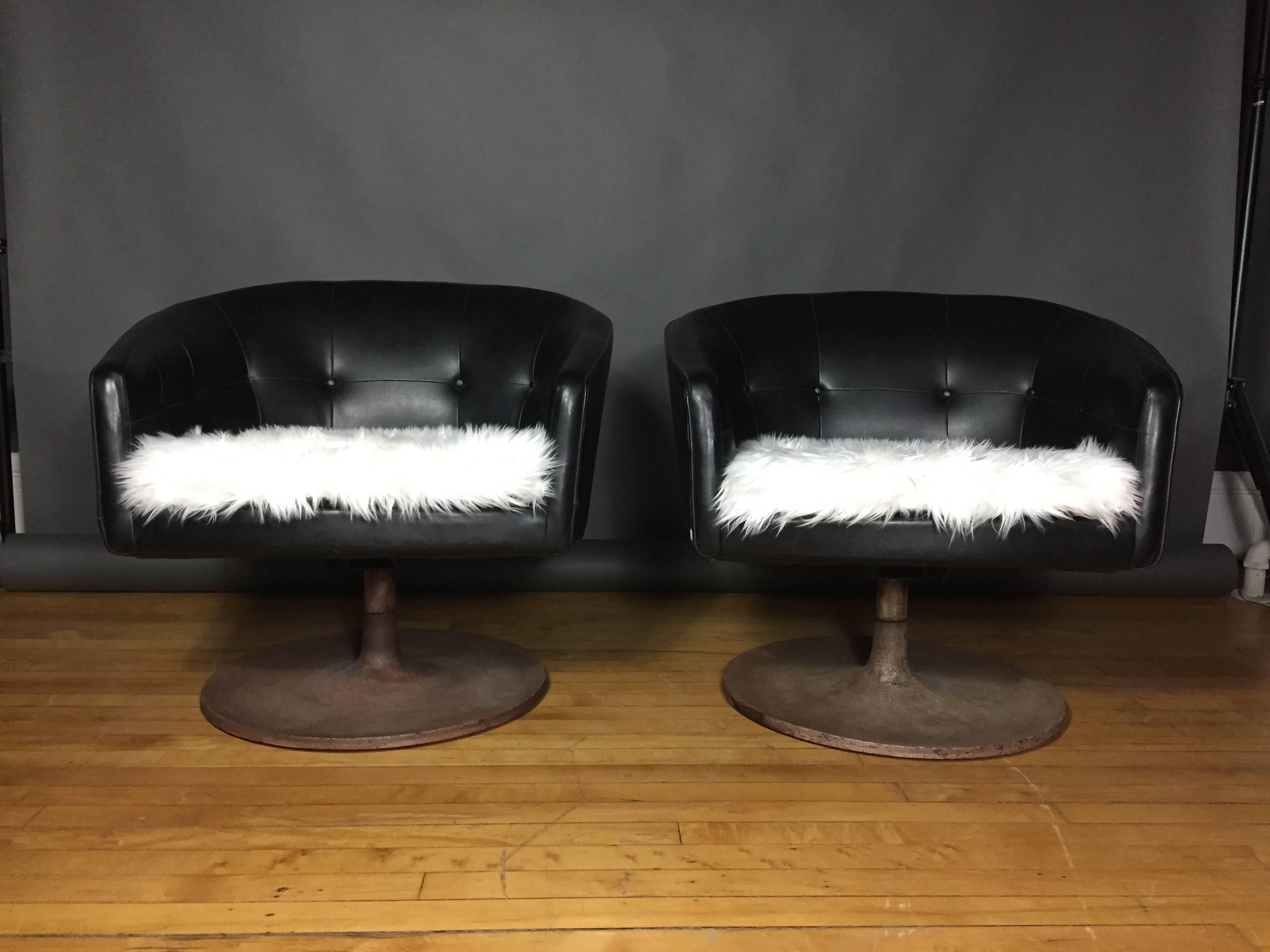 Very sleek pair of lounge chairs by Jens Risom, late 1960s or early 1970s with a low tufted back and frame in black Naugahyde. Contrasting white faux fur seating (not original) and heavy textured metal swivel base. Solid. Two small areas of seam