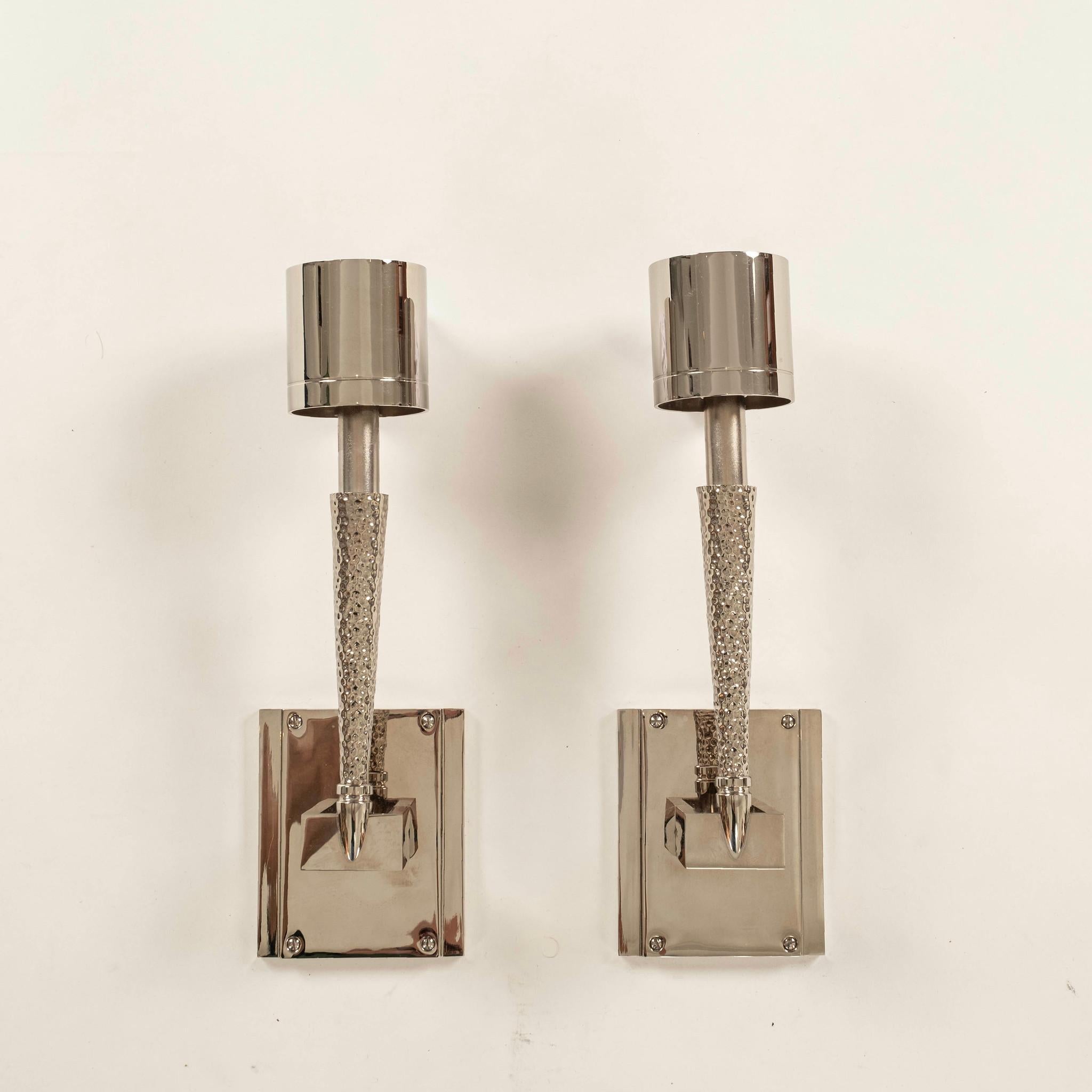 Pair of Jonathan Browning chrome torch sconces featuring an adjustable conical arm with a hammered finish, mounted on rectangular backplates. They are topped with cylindrical chrome shades and incised band detail.