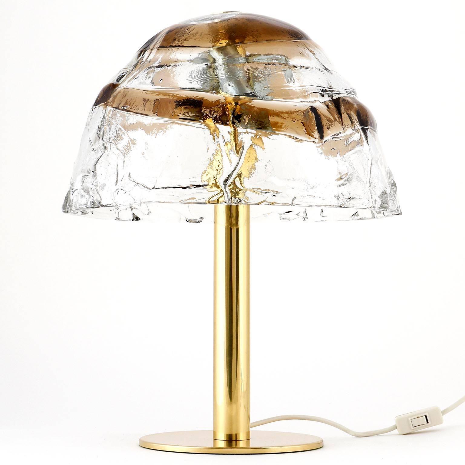 A pair of table lights by J.T. Kalmar, Austria, manufactured in midcentury, circa 1970 (1960s-1970s). A large lamp shade made of clear and smoked or brown glass is held by a brass stand. A nice and large brass bolt holds the glass on top of the