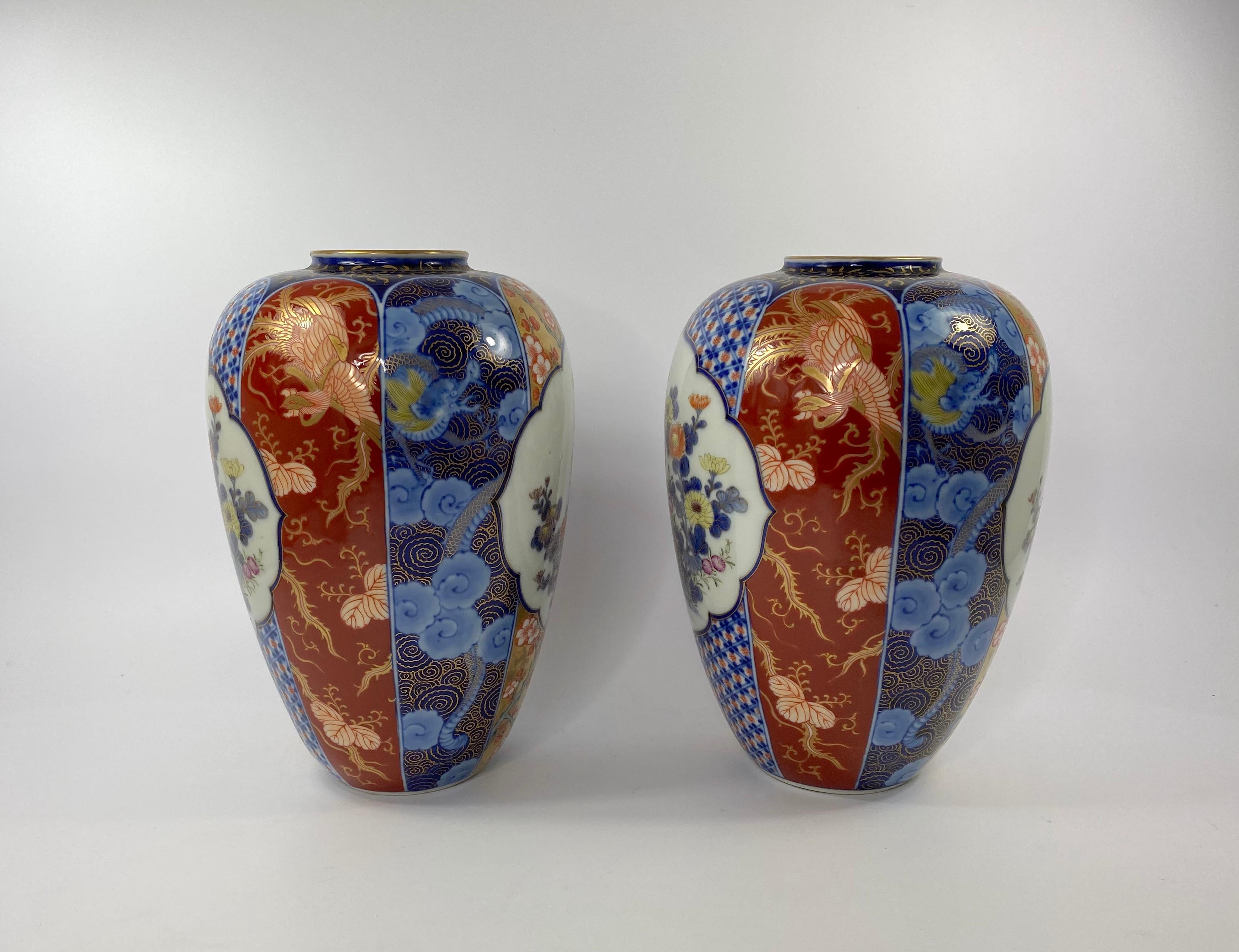 Pair of large Koransha porcelain, Imari vases, Japan, c. 1890. Meiji Period. Both vases finely painted with shaped panels of flowering plants, against a panelled ground of Phoenix, dragons, flowering plants, and textile motif. The flattened necks,