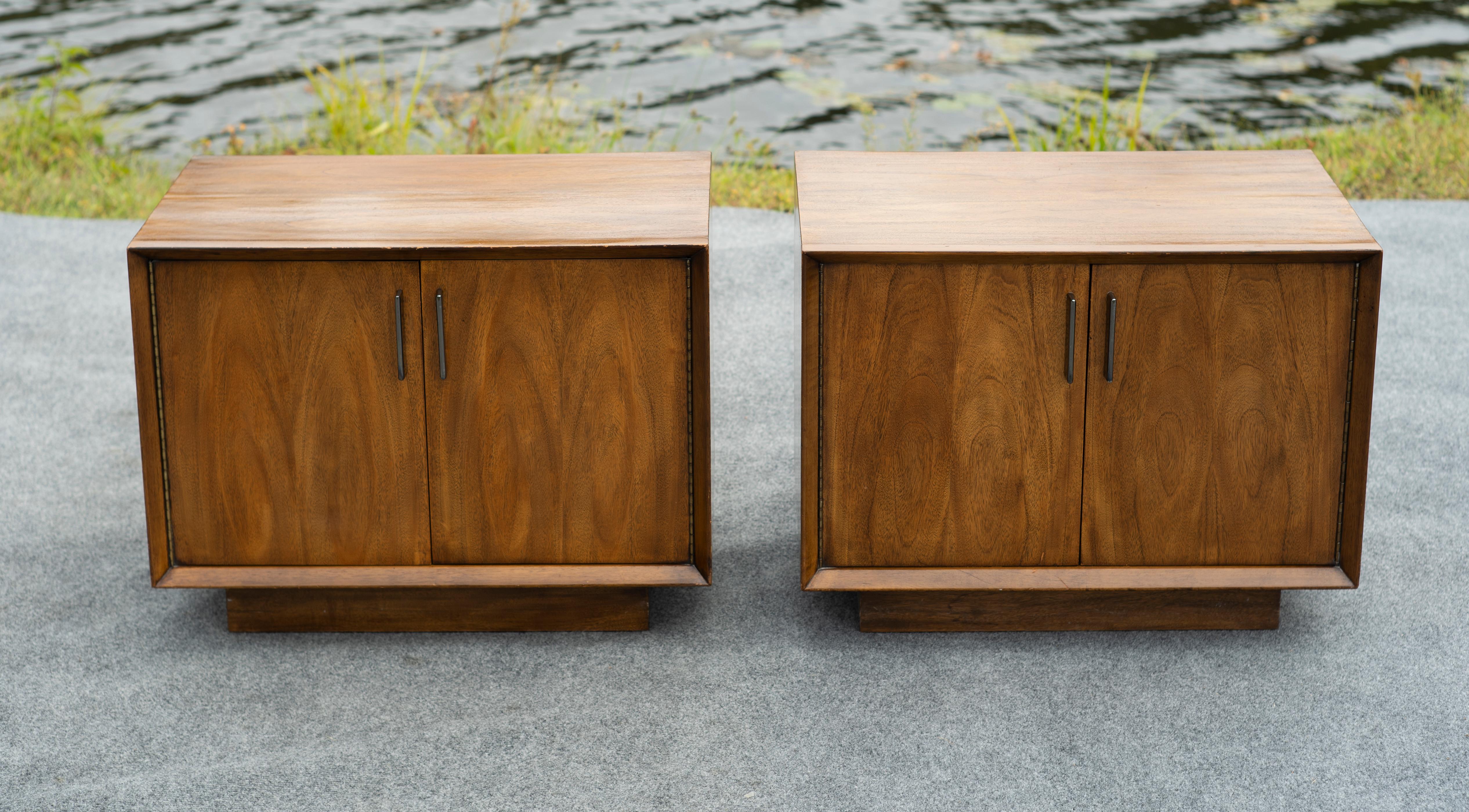 Made in the US in the 1960s, this rare apir of nightstands features a delightful blend of highly textured Paldao walnut and black chrome handles combined with a simplistic yet beautiful and practical design. The doors on each cabinet swing open