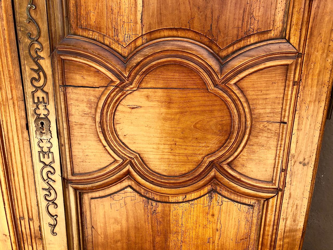This is a great pair of unusually large French 18th century fruitwood armoire doors. The doors feature carved moldings and a carved centered quatrefoil reserve. They retain the original large brass lock plate. Both doors are in overall very good