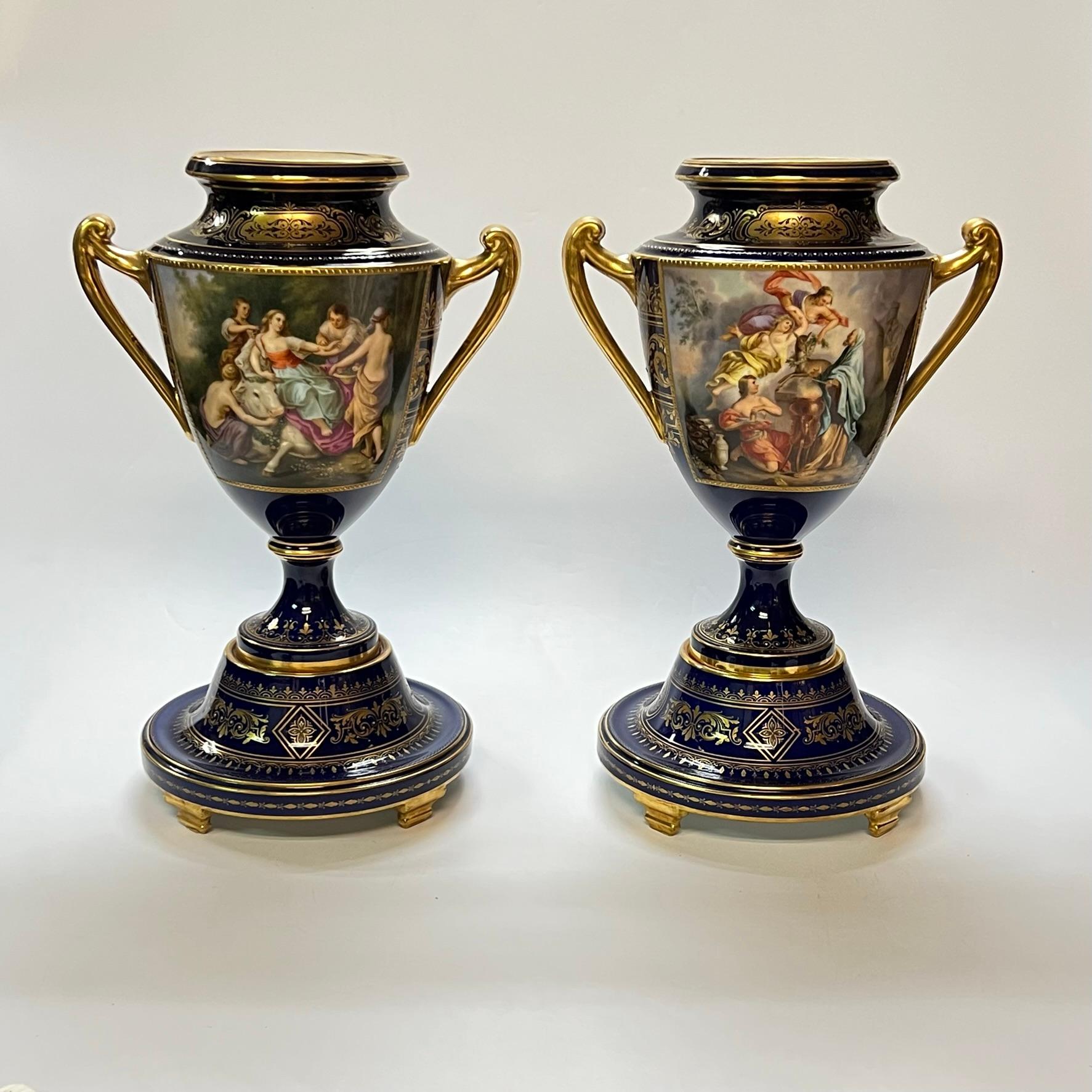 Pair of exceptional, tall handled porcelain vases from Royal Vienna with extensive raised gilding and hand-painted cartouches.  One titled on underside, Opferung der Iphigénie (Sacrifice of Iphigenia).