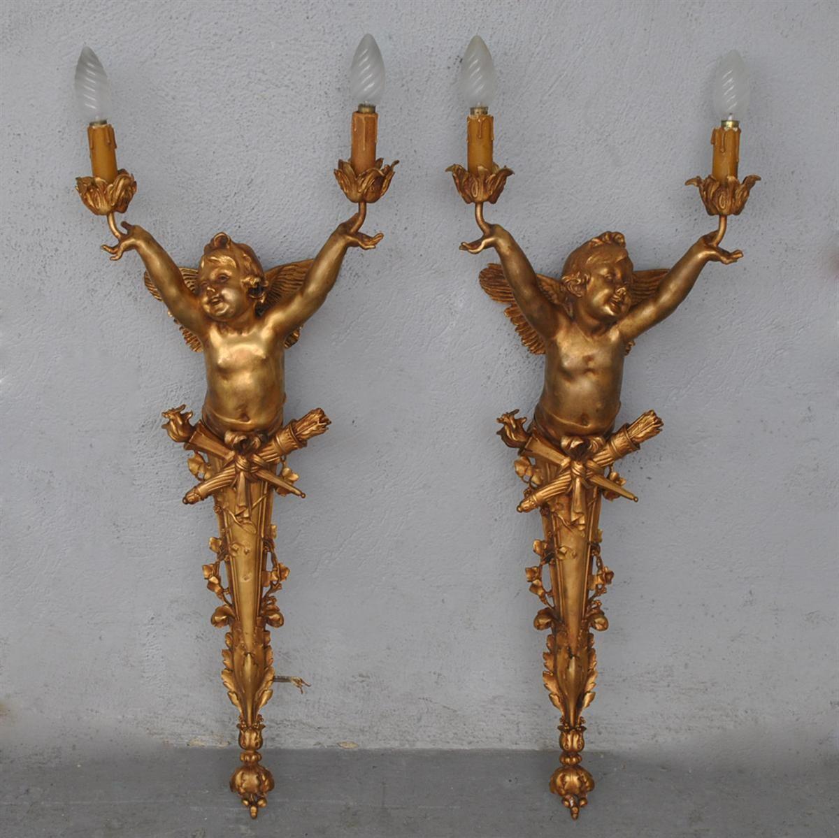 Pair of large Art Nouveau sconces with two branches of light, in gilded bronze. In the shape of a putto with quiver, torch and foliage. Signed 