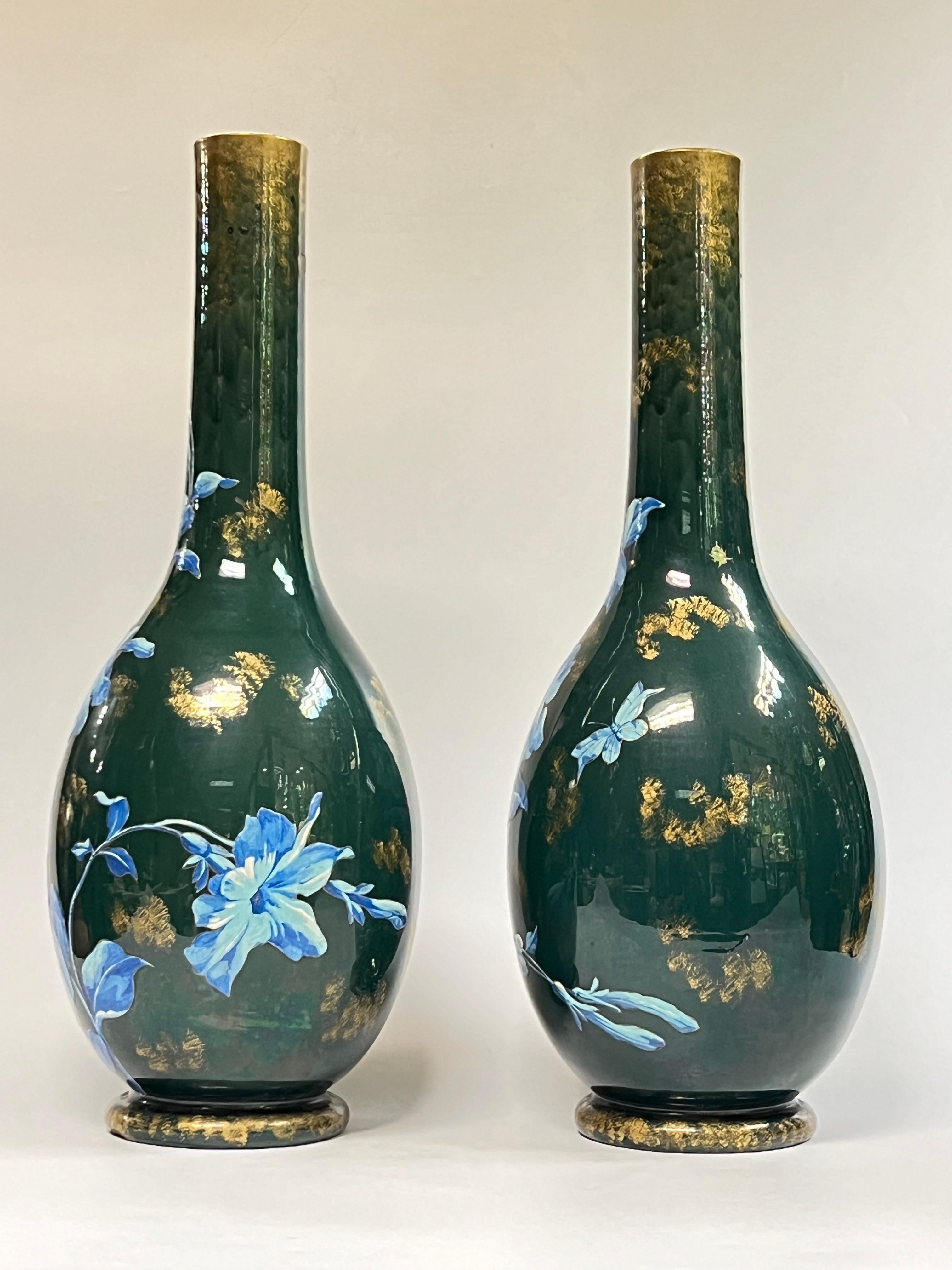 Jolie paire de grands vases anciens en céramique, de 25 3/4 pouces de haut, de style esthétique, avec des fleurs bleues en pleine floraison peintes à la main, des papillons et des accents dorés sur un fond émaillé vert.  Non signée.
