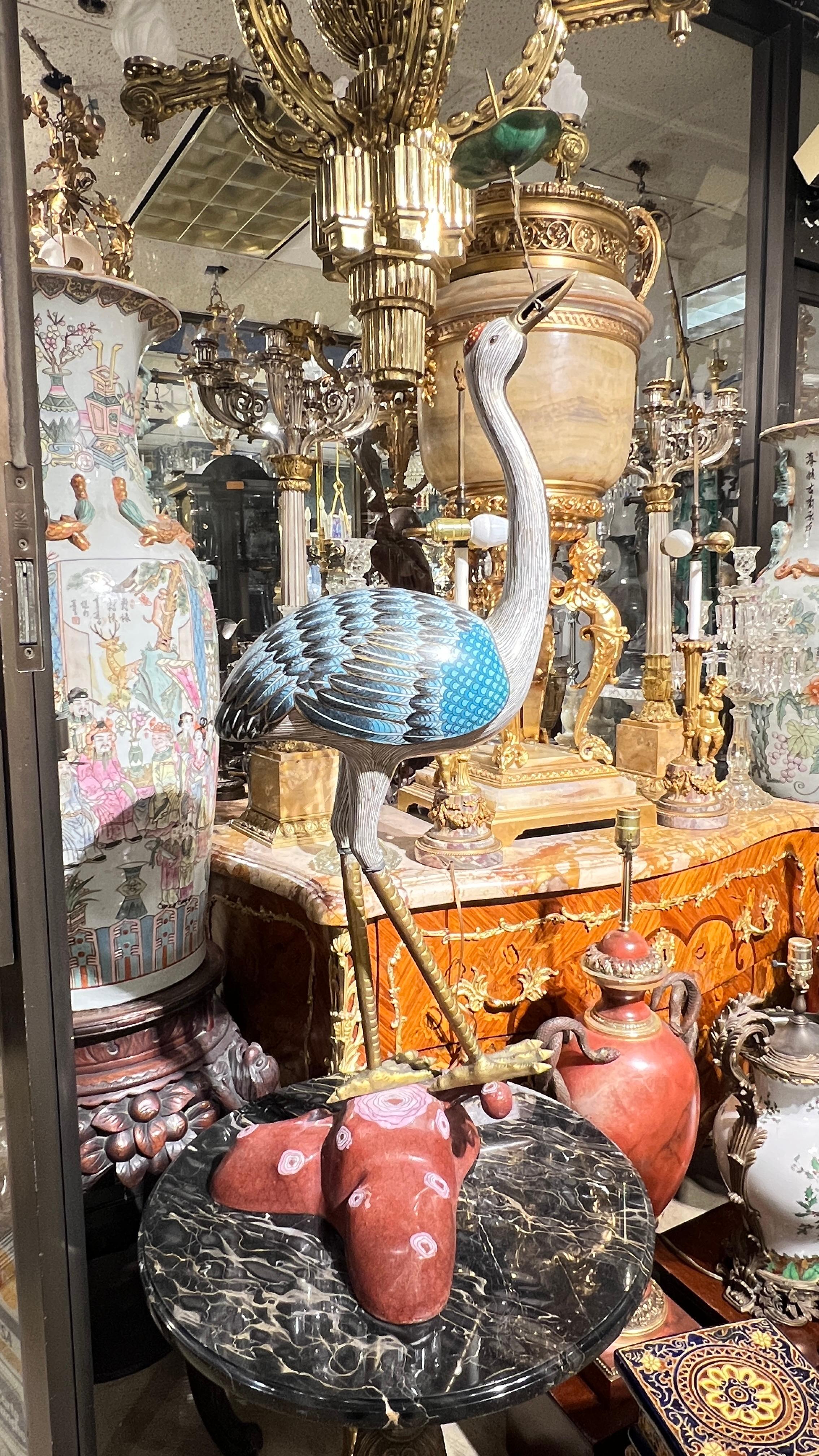 Pair of very large antique Chinese cloisonne enameled metal candle holders fashioned as standing cranes holding prunus branch and lotus leaf in their mouths.  Tops of the bodies removable. 