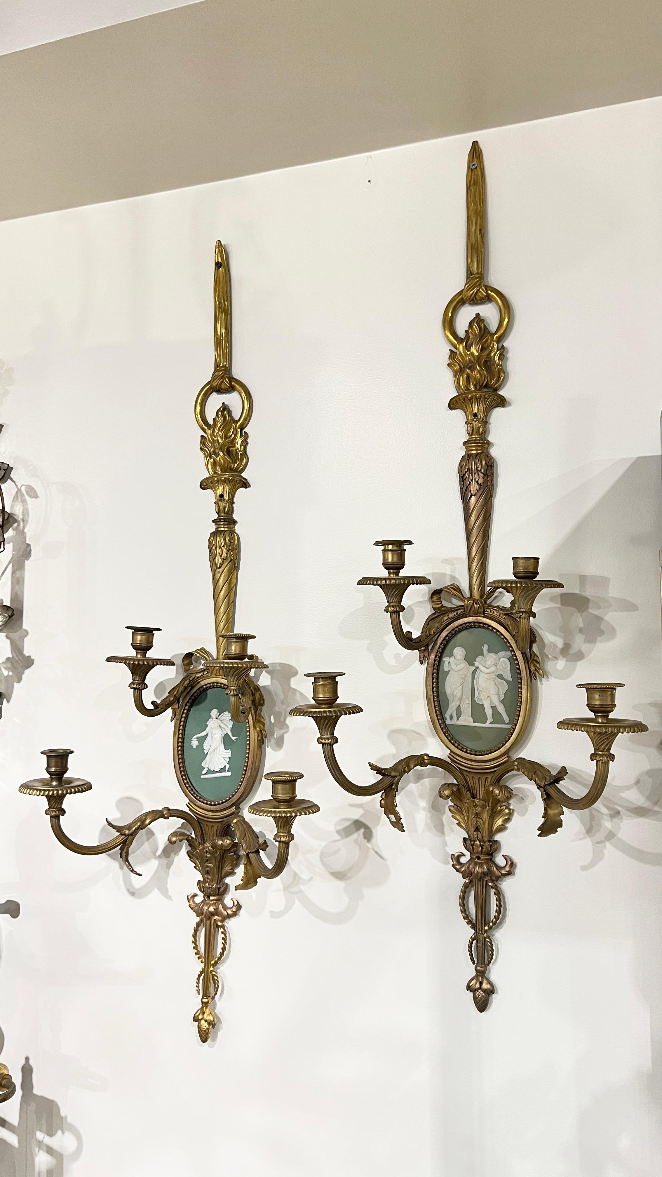 Coppia di antiche (XIX secolo) appliques in bronzo dorato in stile Luigi XVI con placche in porcellana diaspro bianco e verde foresta di forma ovale raffiguranti putti e una musa danzante, forse di Wedgwood, con quattro bracci a candela e vari