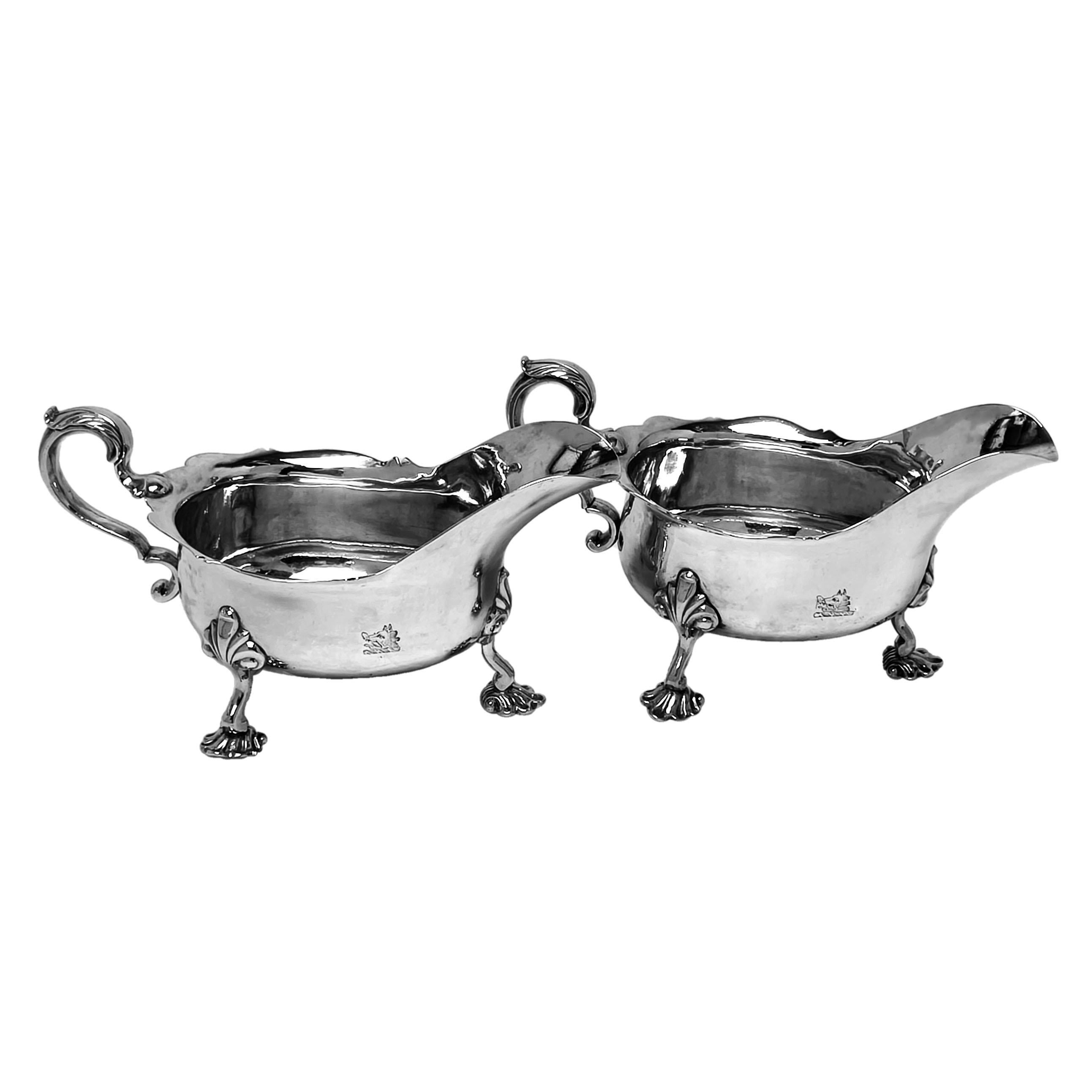 A pair of large Antique Irish George II Silver Sauce Boats in a classic bellied style with everted rims and acanthus leaf topped scroll handles. Each Irish Sterling Silver Gravy Boat stands on three stylised shell feet with shell capitals. Each