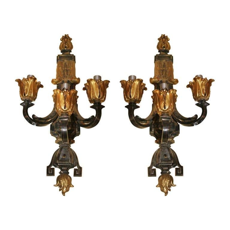 Paire de grandes appliques anciennes (début du 20e siècle) en bronze doré et patiné à trois lumières, à la manière d'Edward Caldwell, mesurant 28 x 13 x 9 1/2 pouces, avec des bougeoirs en forme de tulipe et divers motifs néoclassiques, dont une