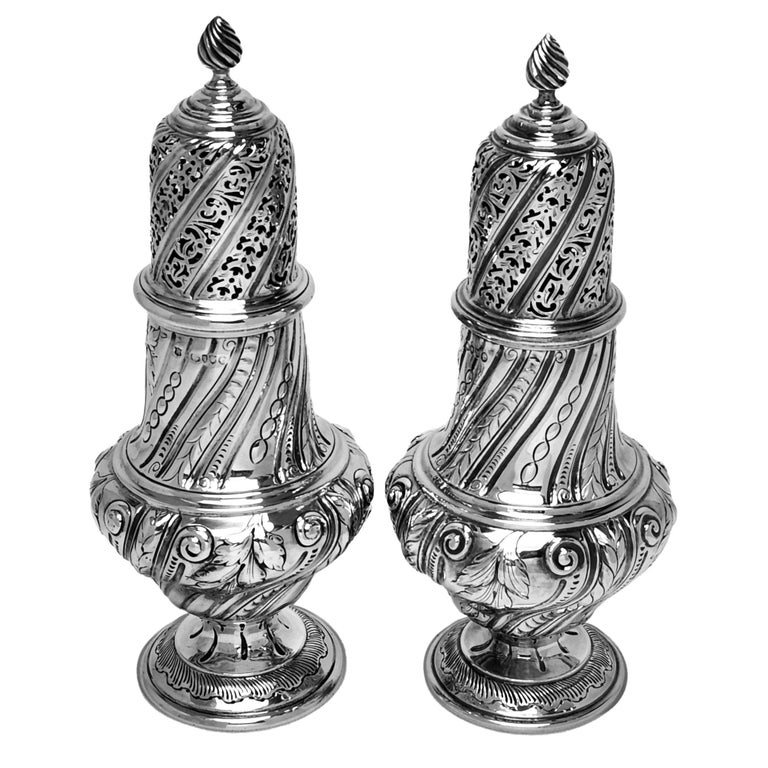 A pair of large antique Victorian silver casters in a classic baluster shape and standing on a spread pedestal foot. The body of the caster is decorate with a writhen fluted shape that is mirrored on the push fit lid. The body, lid and foot of the