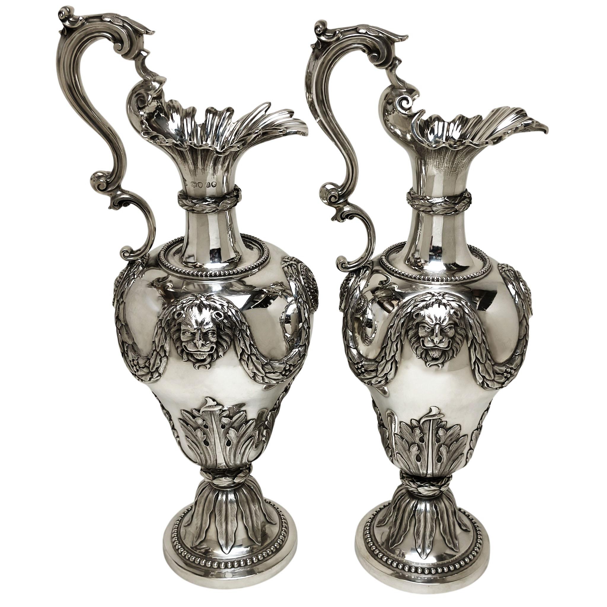 Una coppia di magnifici Eleg antichi vittoriani in argento massiccio con eleganti disegni cesellati. Il corpo della brocca d'argento presenta un disegno a cesello ornato da una coppia di teste di leone e da una coppia di cartigli ornati. La parte