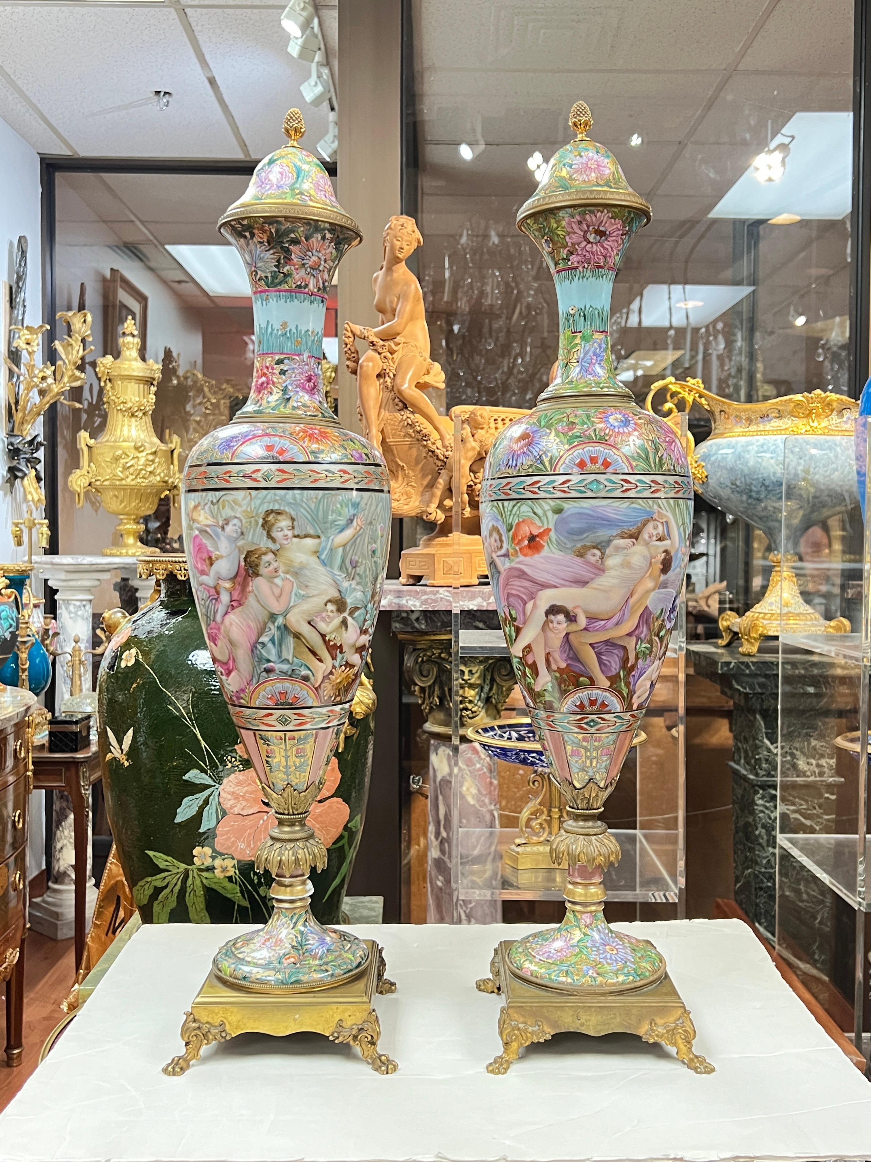 Notre paire de vases de style Sèvres montés sur bronze doré se distingue par ses extraordinaires motifs en émail pseudo-cloisonné et ses portraits exquis de jeunes filles, de déesses néoclassiques et de chérubins s'ébattant.  Chacune mesure 32 1/2
