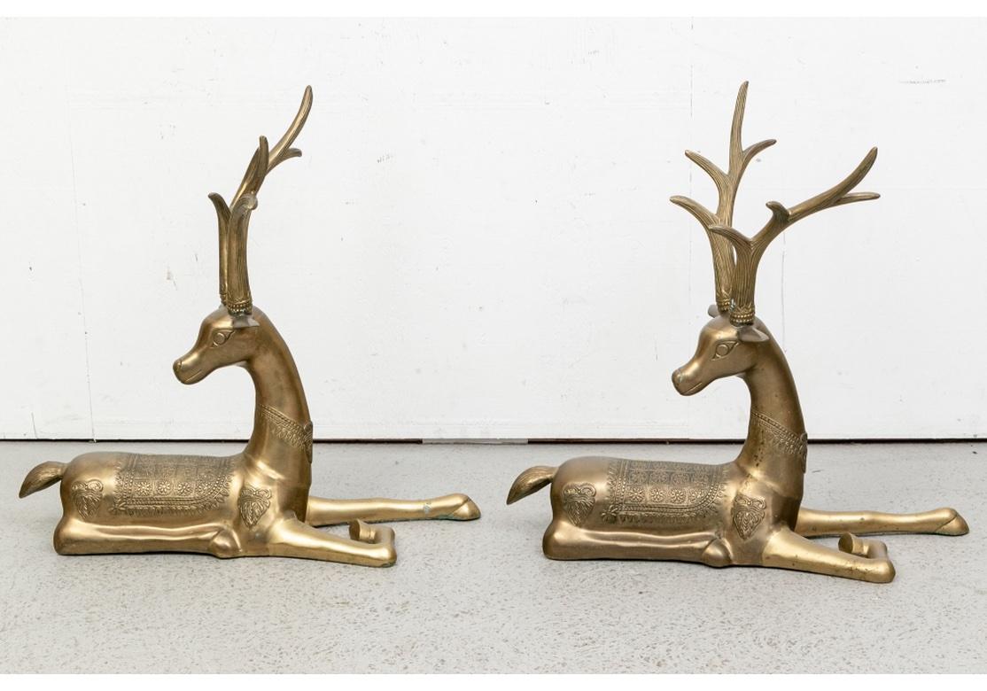 A large and very decorative Vintage Brass Stag Pair in reclining position.Perhaps mythological creatures, each recumbent with patterned saddles with rosettes and fringe and foliate appliques on the sides. They wear necklaces and have tall ribbed