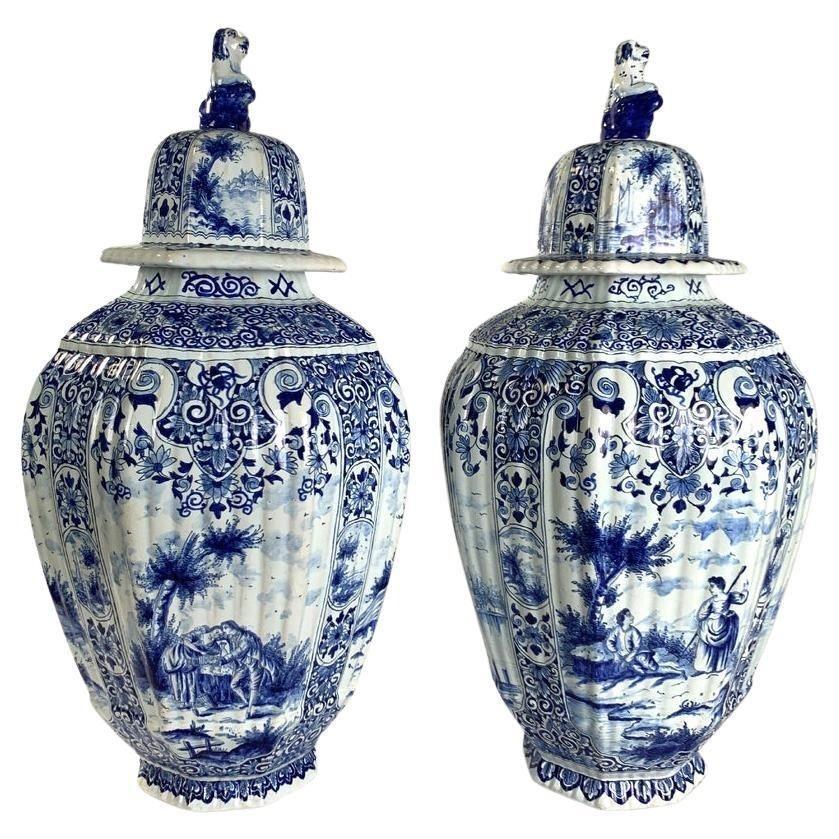 Each of these large blue and white Dutch Delft jars is decorated with four unique romantic scenes in panels.
The scenes feature couples in 18th-century attire, scenes by the riverbank, and sailboats on the water.
The panels are filled with deep blue