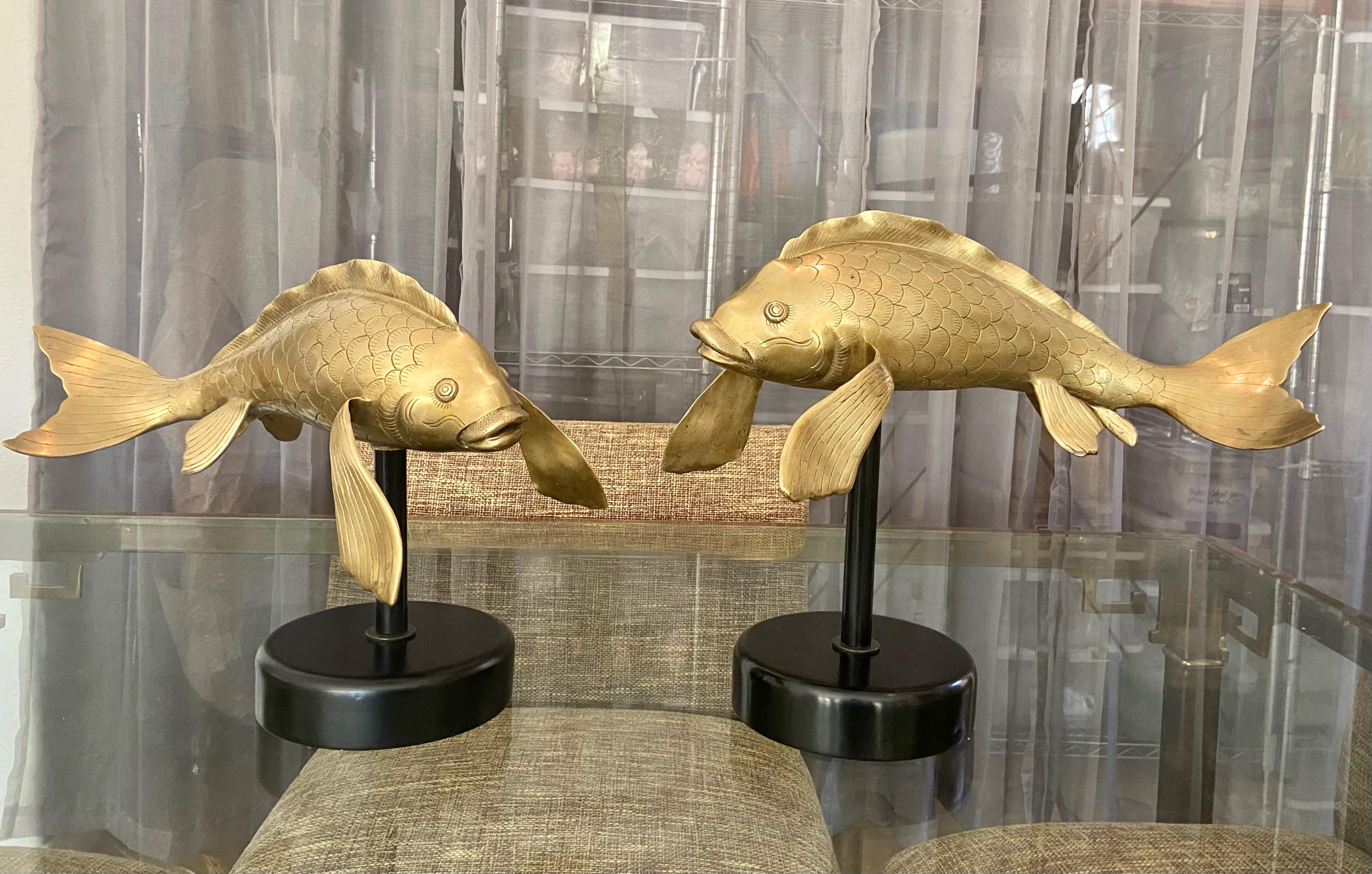 Pair of large Asian heavy cast brass koi fish sculptors newly mounted on black lacquered wood and metal bases. Each fish is finely crafted and sightly different in size. The bases are slightly different in height giving the impression they are