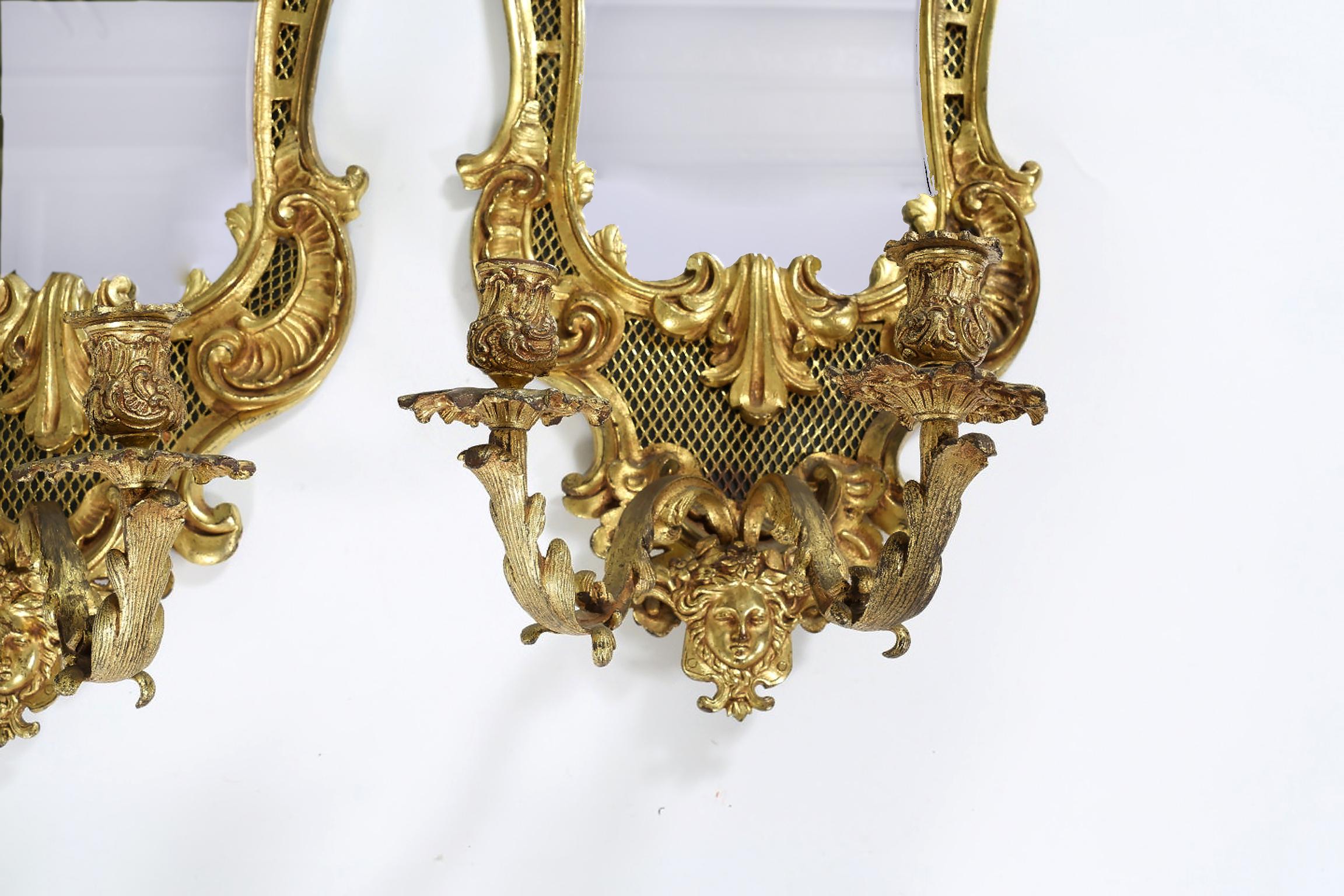 Pair of large bronze mirrored back sconces with two armed lights. Each one is in good condition with minor wear consistent with age / use. Each one measure about 24 inches high x 13 inches wide.