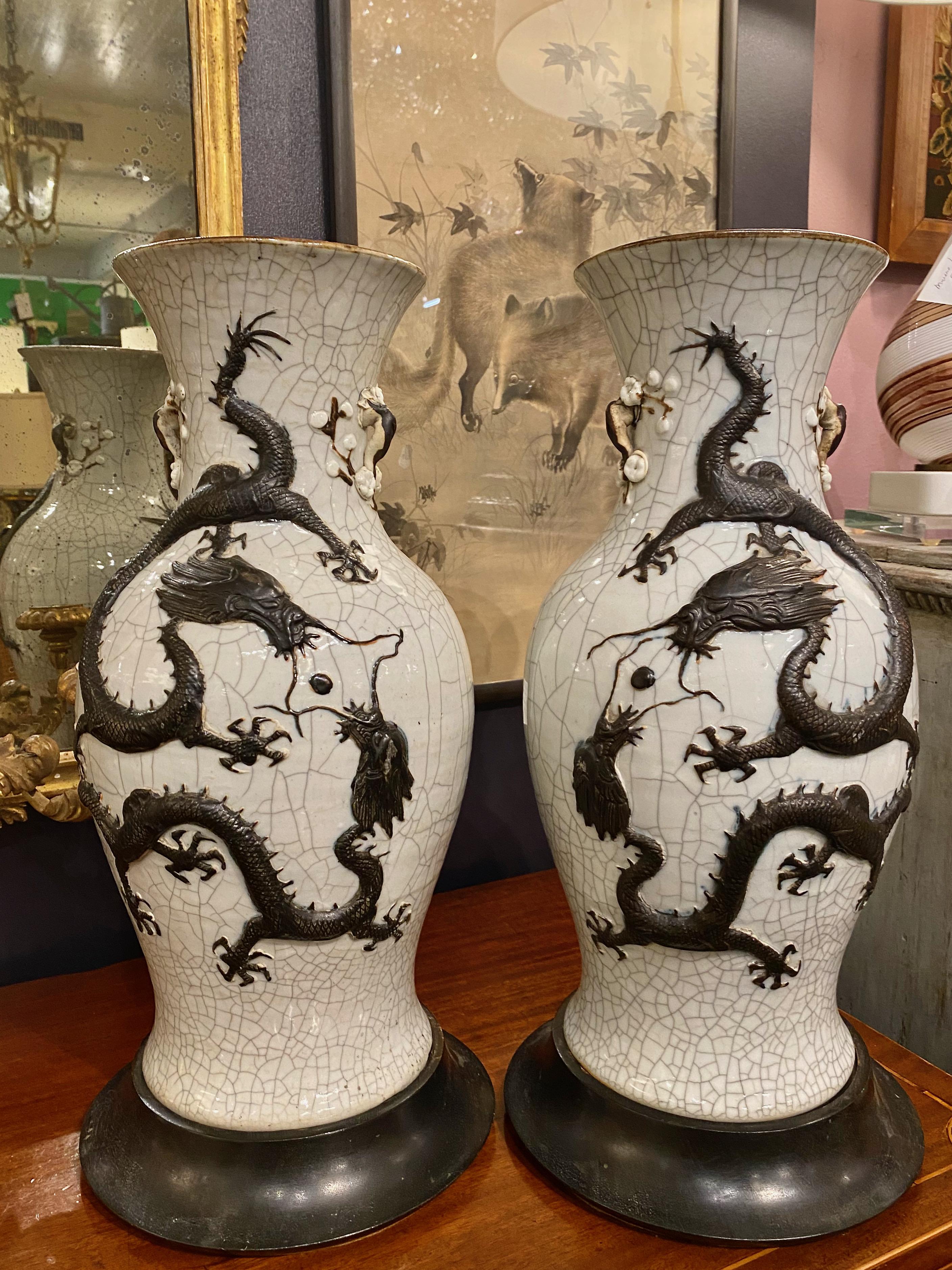This is a very large and stunning pair of late 19th century Chinese Pale Celadon Crackle Glazed Dragon and Flaming Pearl Vases. The well-sculpted dragons are applied to the body of the vases and are highlighted in a dark-charcoal brown. The side