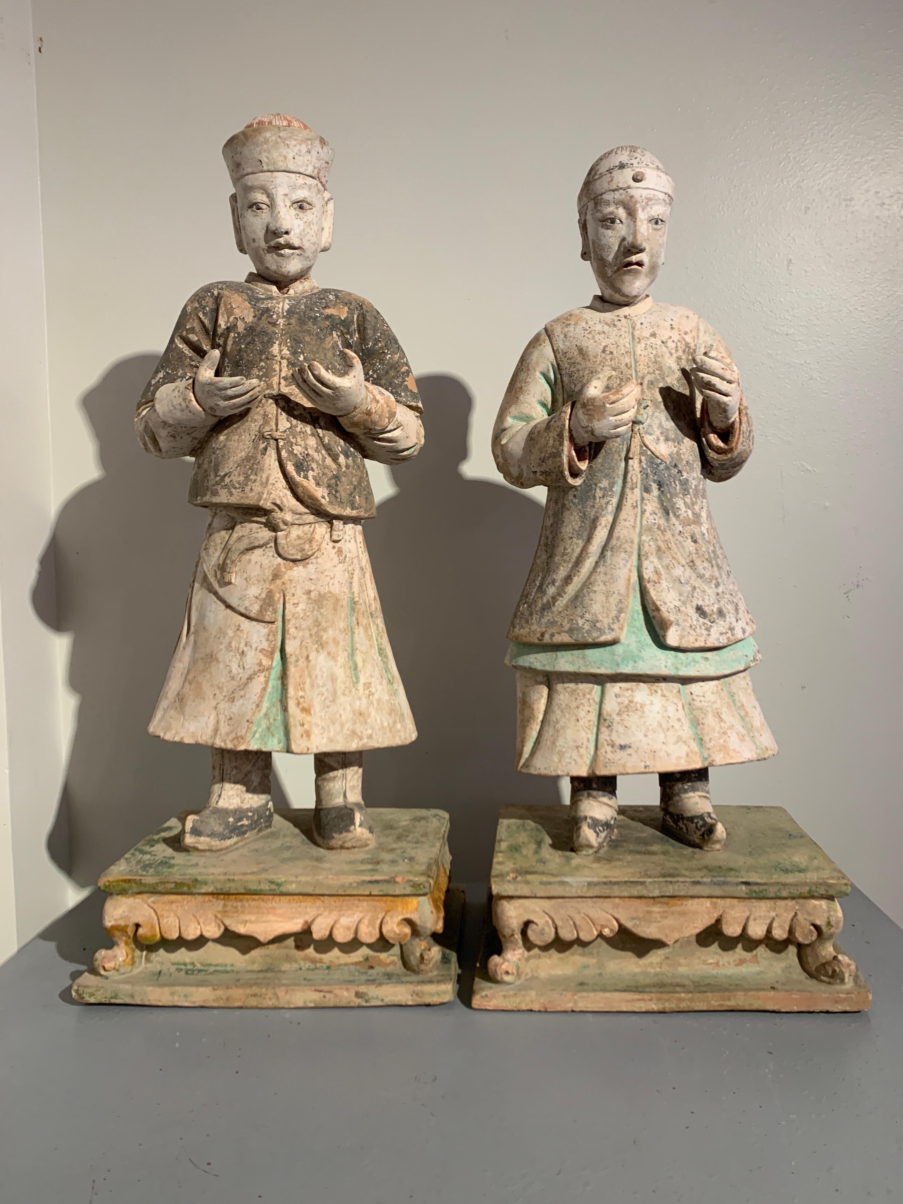 A striking pair of large Chinese glazed and painted pottery figures, Ming Dynasty (1368 to 1644), circa 16th century, China.

The impressive and realistically modeled figures each portrayed standing upright upon a sancai (three color) glazed