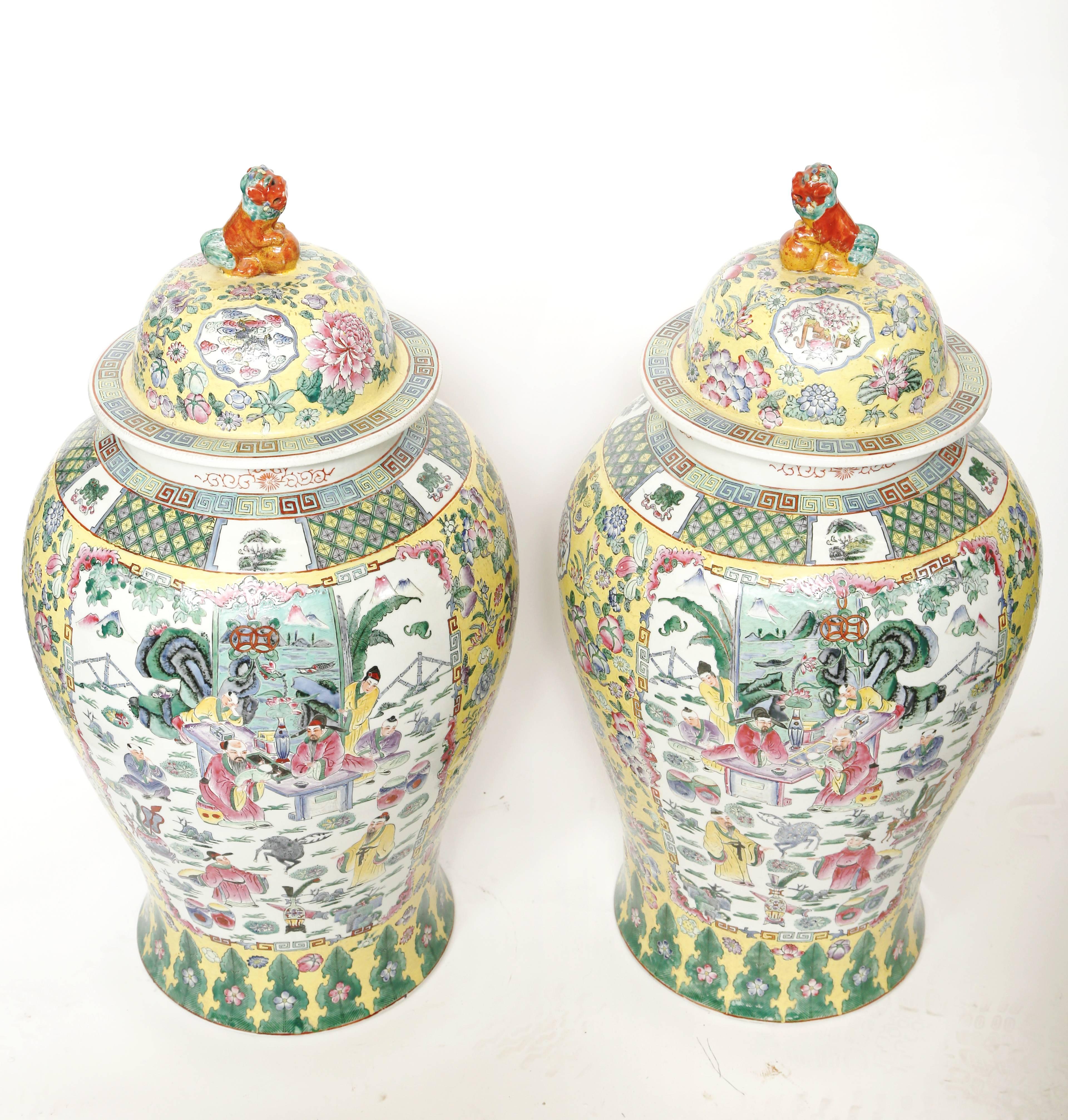 Pair or very large Chinese porcelain temple jars. The jars are hand decorated in lovely pastel colors with a pair of mirror image scenes on the front and back. The sides are decorated with floral images. The lids have an iron red foo lion on top.