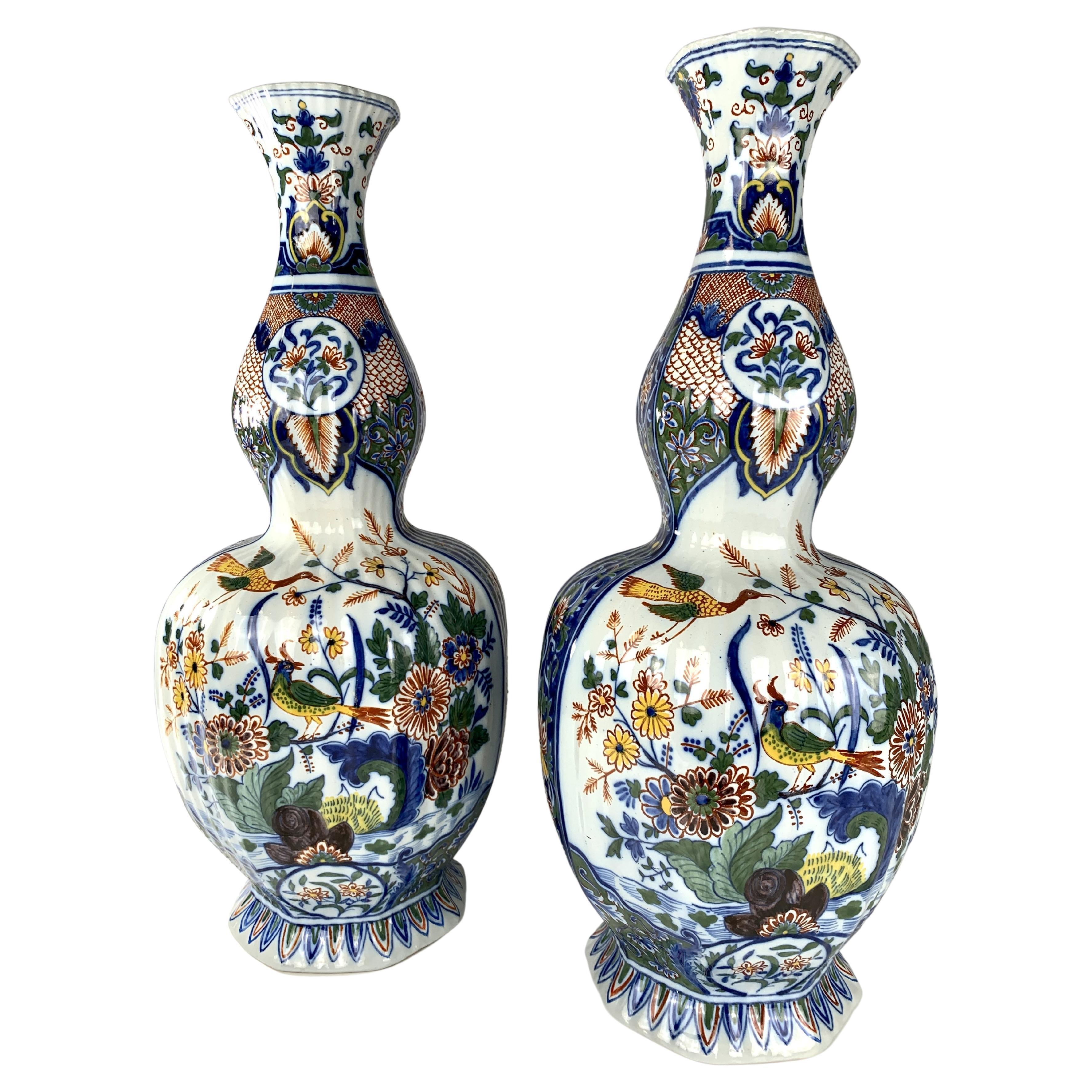 Made in the Netherlands circa 1880, this lovely pair of Dutch Delft mantle vases have a traditional double gourd shape.  
The vases were painted in traditional polychrome colors showing a waterside scene filled with flowers and songbirds. 
Panels