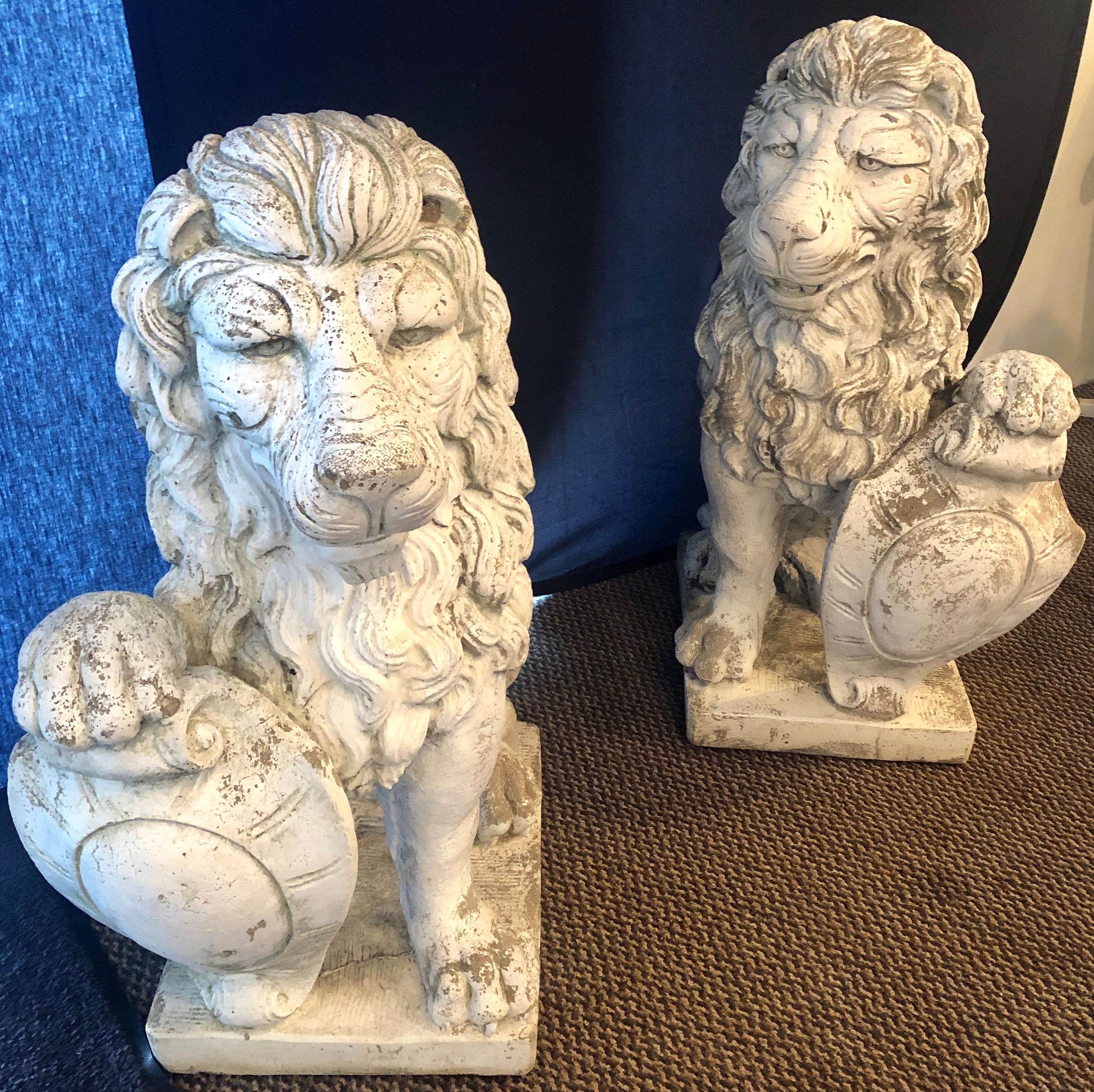 Pair of detailed cast stone shielded entrance lions. These large and detailed lions face each other and come from a fine Greenwich Mansion. Each signed on the base. Henri the worlds leading name in cast stone fountains and garden decor. Today, that
