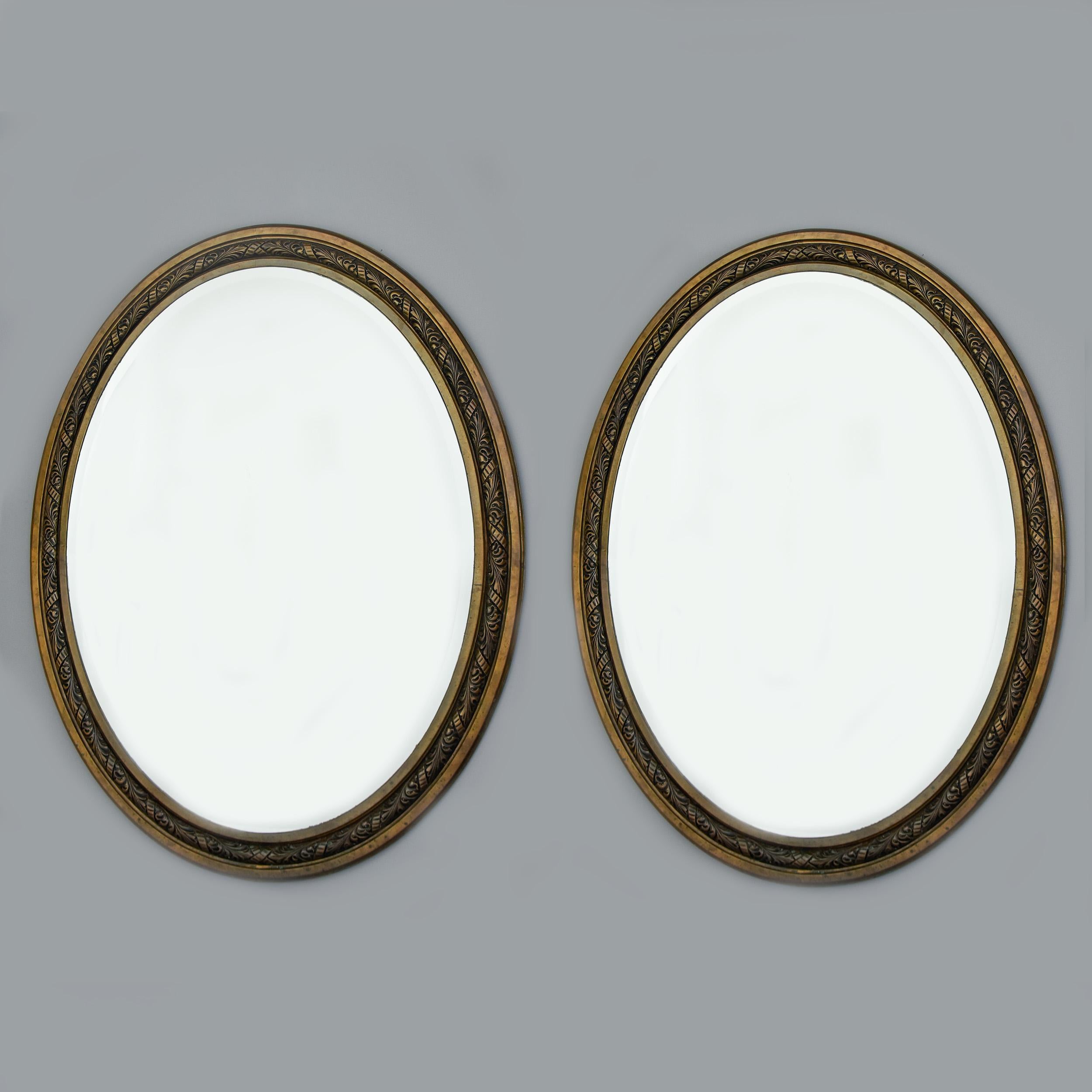 Large pair of Art Nouveau French oval mirrors in bronze frames that date from approximately 1910. Frames are 57” high and 45” wide with actual mirrors measuring 49” high X 36.5” wide. Mirrors have beveled outer edge. Cast bronze frames have patina