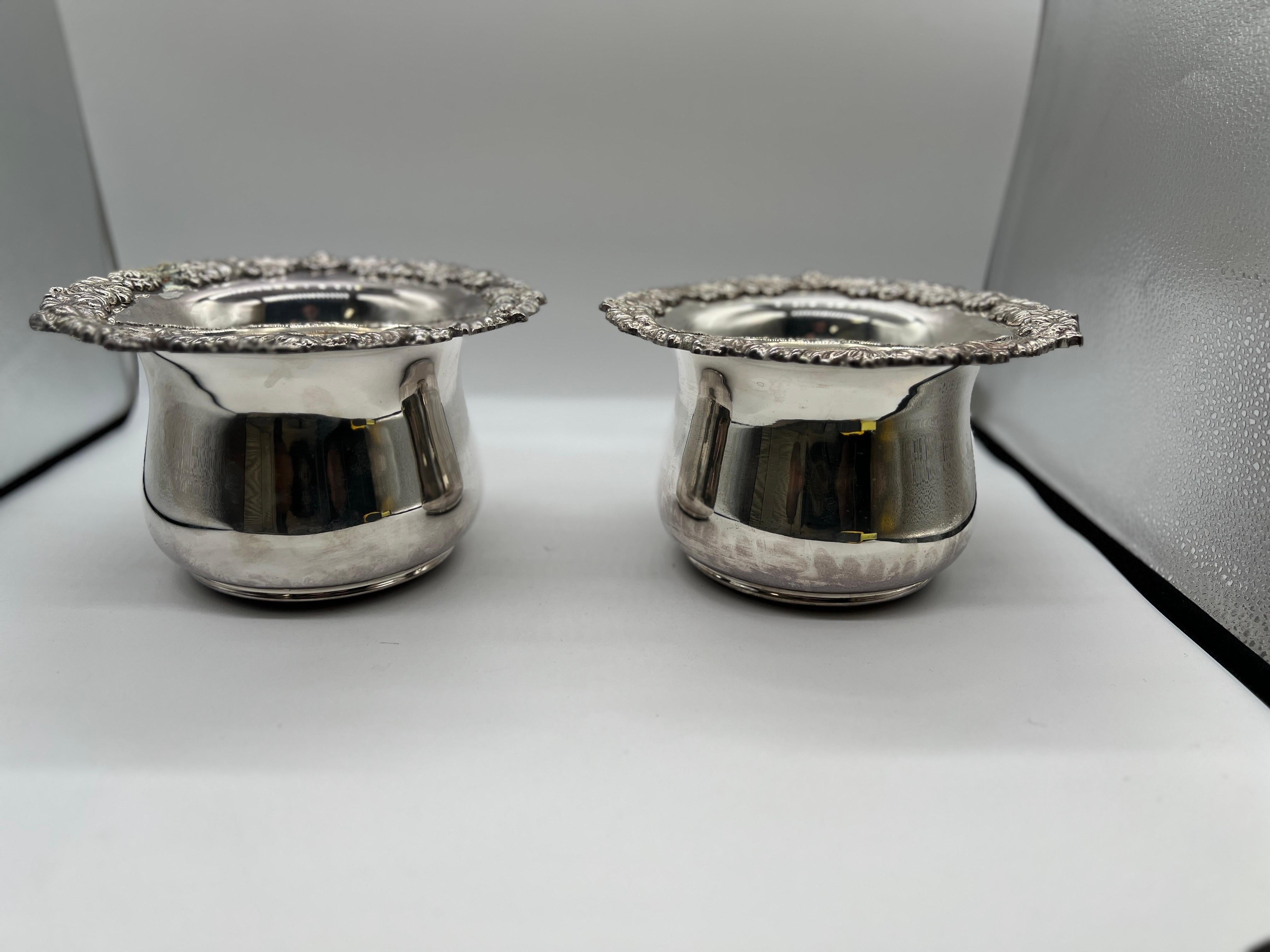 A pair of large Royal Castle silverplated bottle holders or coasters with floral and rococo style banding to the border rim. Each marked to interior of bowl and made in Sheffield England.