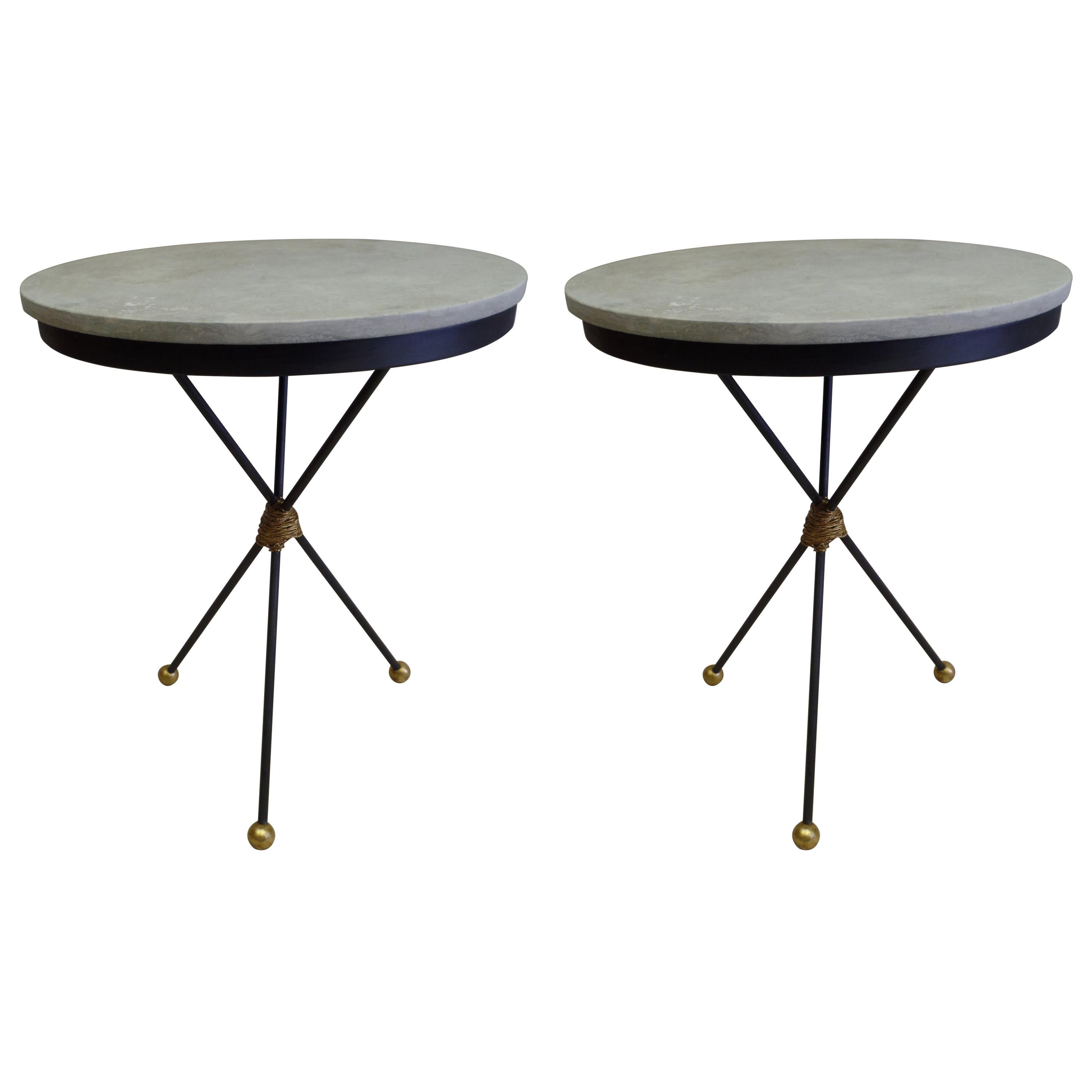 Elegant Pair of French Mid-Century Modern Neoclassical partially gilt wrought iron tables in the style of Gilbert Poillerat. The tables have silver-grey travertine tops supported by a tripod base ending with three gilt iron ball feet. The size of