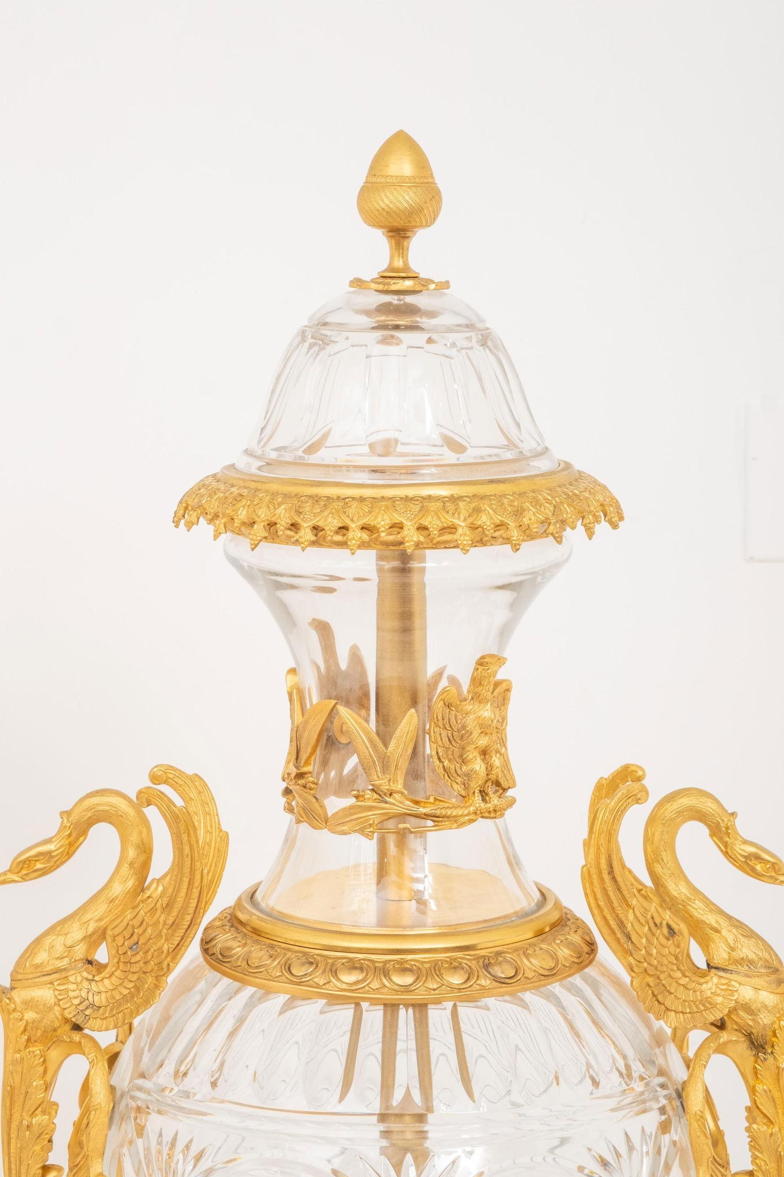 Coppia di urne o vasi in vetro cristallino francese molto grandi (alti 45 pollici), montati su bronzo dorato, di forma ovoidale, con motivi a gadrooning sulla spalla e motivi guilloche stilizzati intorno alla vita, con decorazioni in bronzo dorato