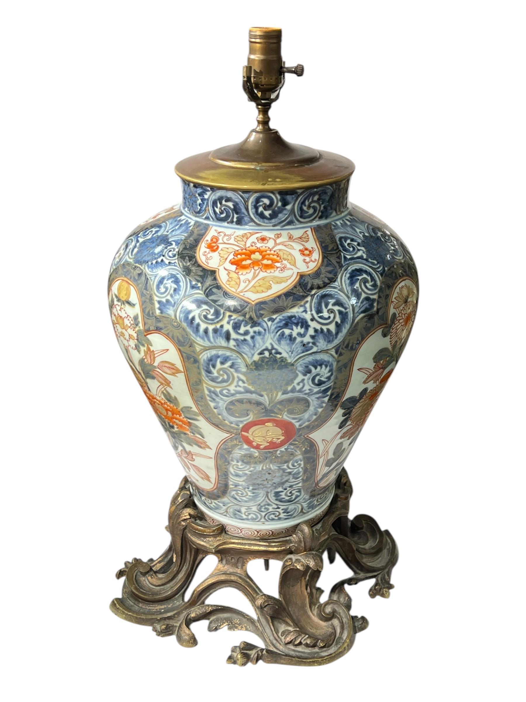 Pair of large antique table lamps fashioned from large Japanese Imari porcelain vases with beautiful floral designs, mounted on organic styles patinated bronze bases.  Each 24 1/2 inches tall and 12 inches across with sockets and wiring and cords,