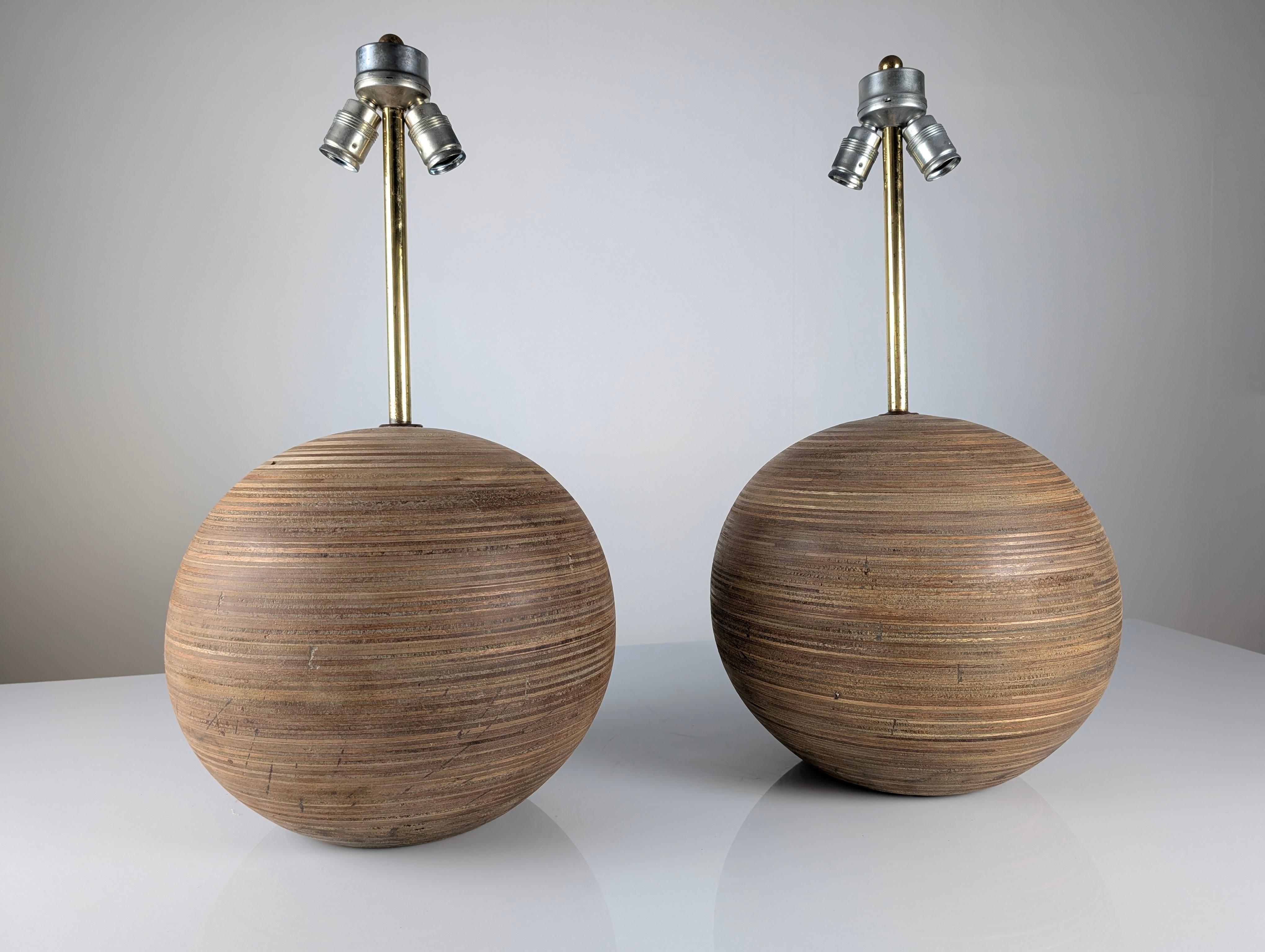 Pair large table lamp from the 1960s featuring a spherical base made of layered laminated wood, creating a beautiful and intricate wood grain pattern that adds texture and depth to the design. Its dual lighting system is elegantly elevated by a