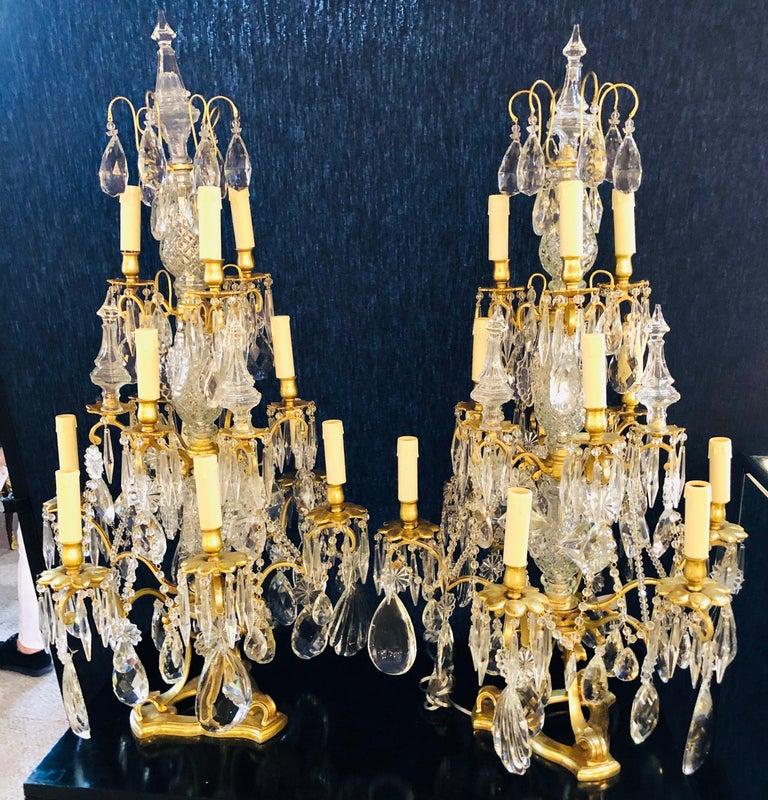Pair of monumental Louis XVI style candelabrum table lamps brass and crystal each having twelve light. The crystal triple column-form center having three tiers of lights stemming from the center the whole supported by a brass tripod base. The