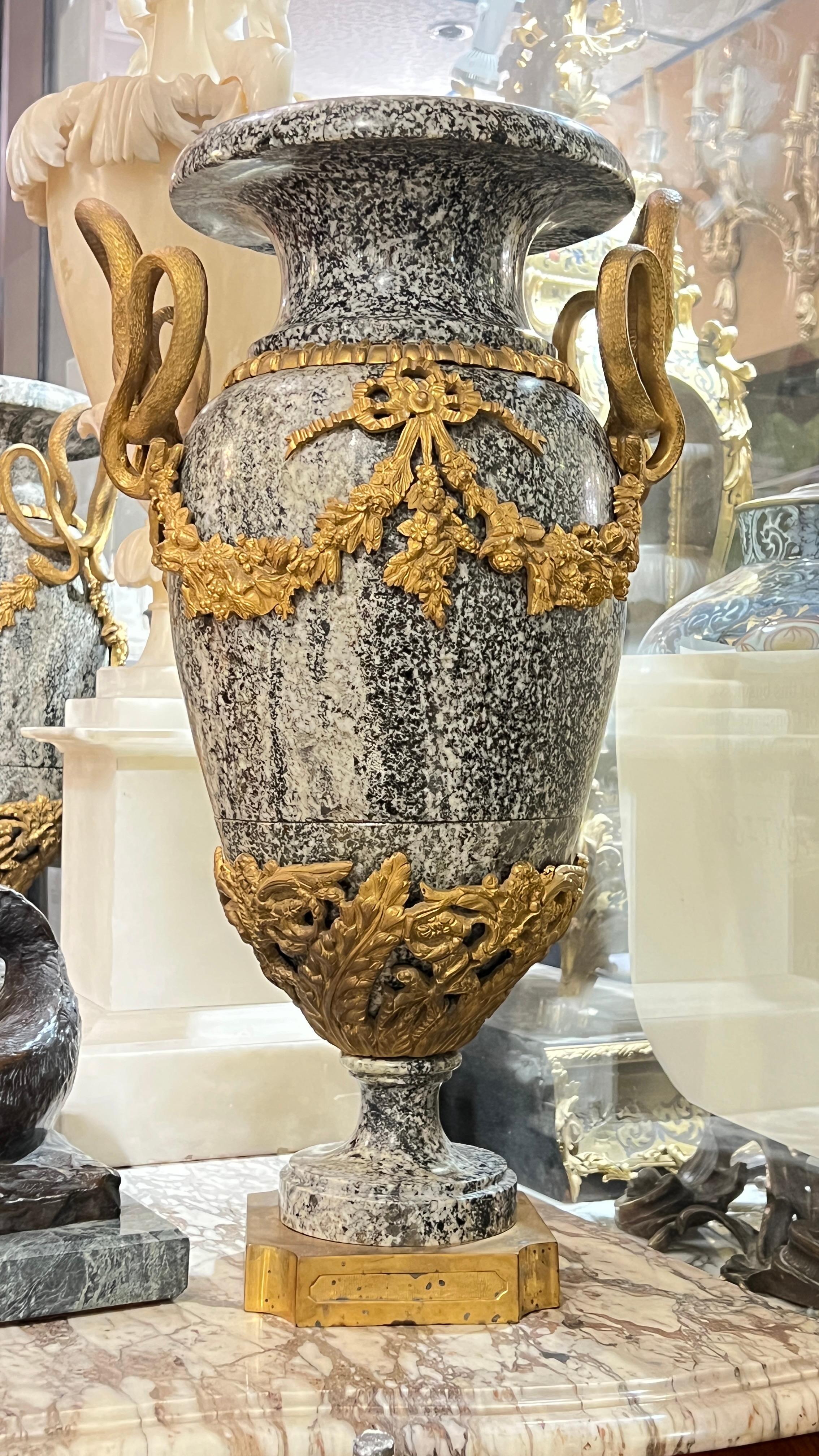 Pair antique (19th century) French Vases crafted from variegated white and charcoal marble with gilt bronze mounts including large snake-form handles, tied ribbons and floral swags, mounted on gilt bronze pedestals.  Each 23 1/4 inches tall.