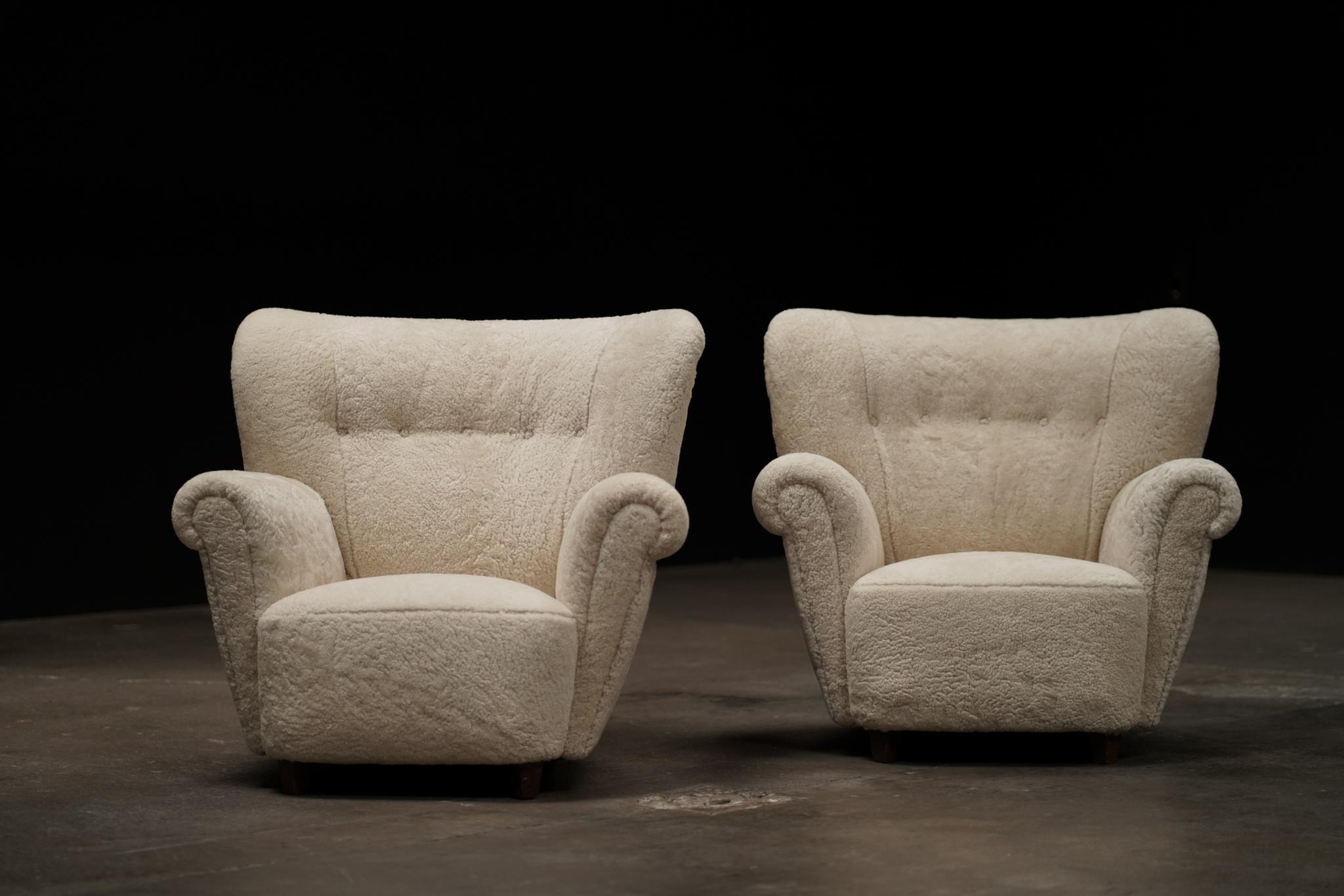 This pair of large Danish lounge chairs has been reupholstered in luxurious ivory shearling, offering inviting texture and warmth. With generous proportions and sculptural lines, they balance comfort with understated sophistication.