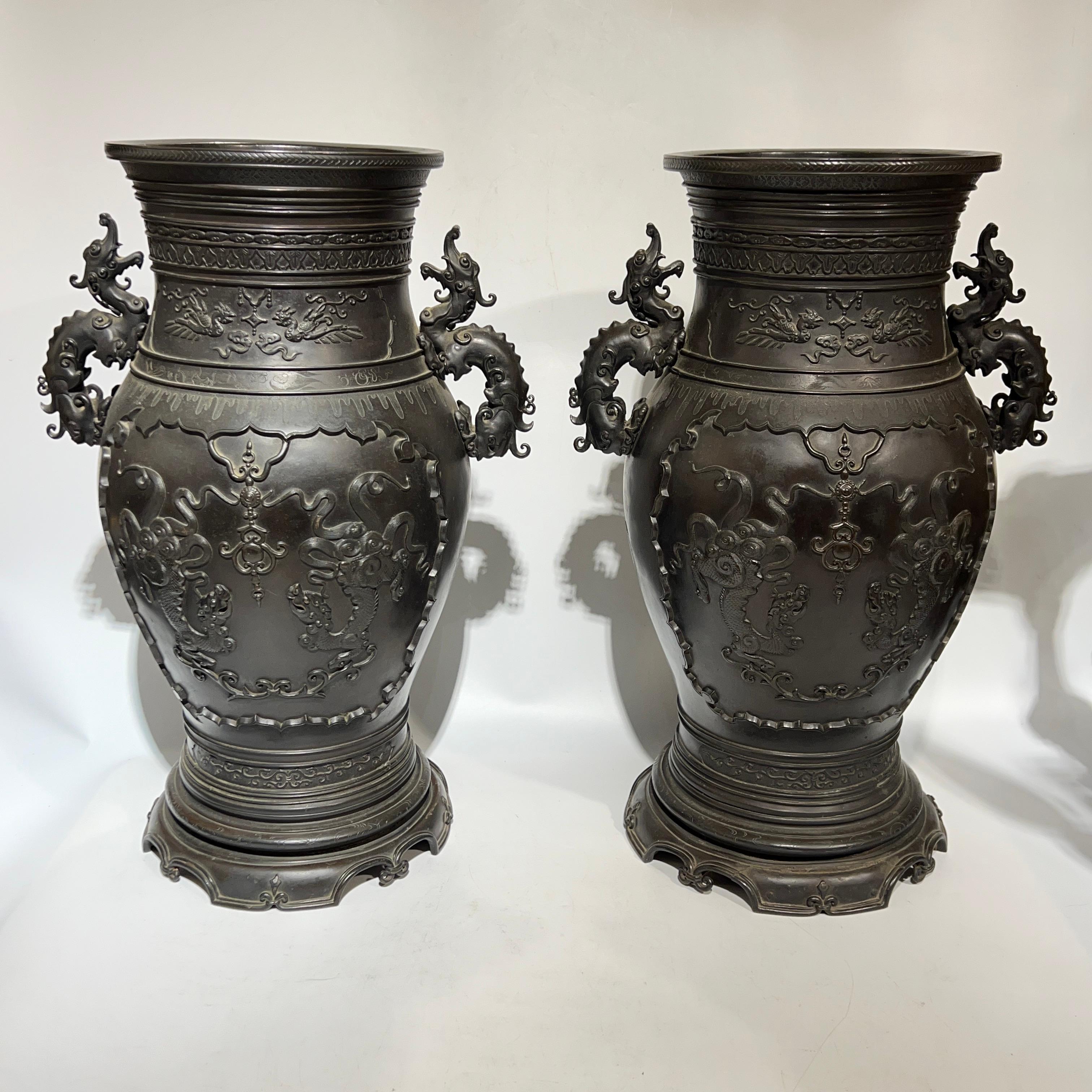 Pair of very fine Meiji period Japanese bronze vases with dark brown patina with dragon handles and exceptional designs of grotesque mythological figures.  23 1/4 inches tall and each in very good condition. 