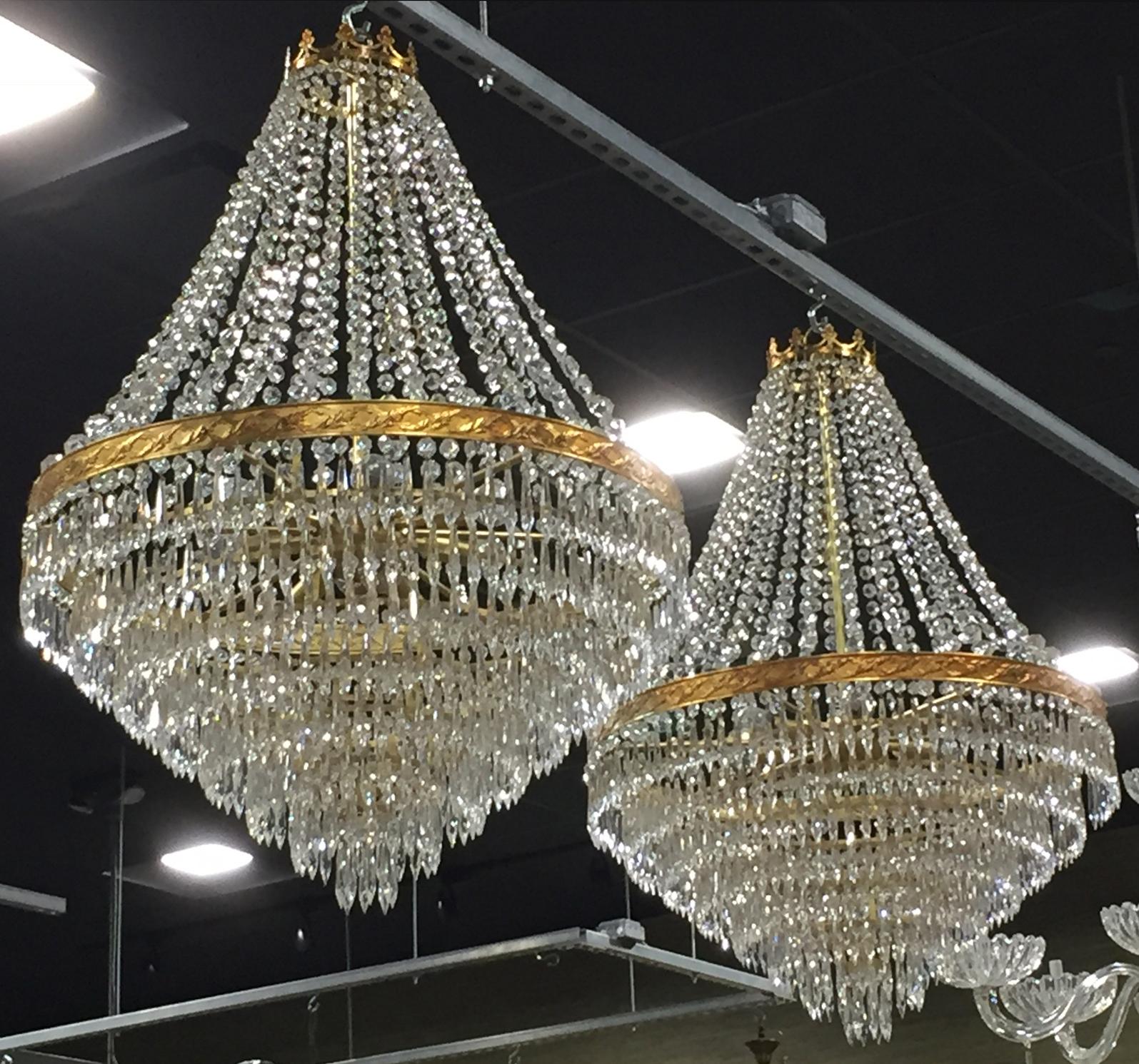 Pair of circa 1980s Italian wedding cake style chandeliers that each have eight tiers of crystal pendants and nine candelabra sockets. The decorative brass frames support draped crystal swags and chandeliers are topped with brass crown. New wiring