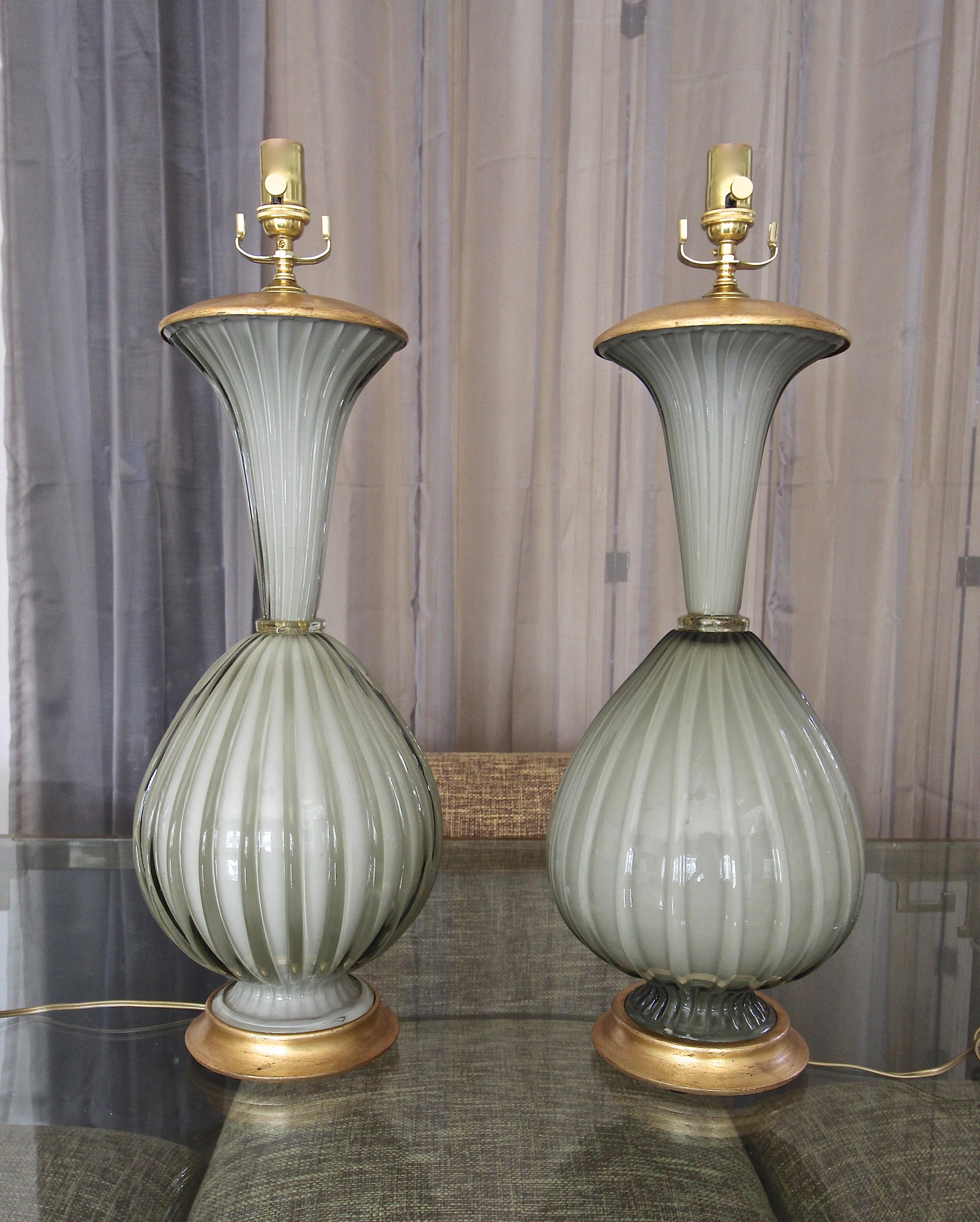 Similar pair of large Italian Murano hand blown grey (or olive grey) ribbed cased colored glass table lamps by Marbro. The thick and heavy crafted glass amps are resting on custom giltwood bases, with matching gilt metal vase caps. Newly wired with