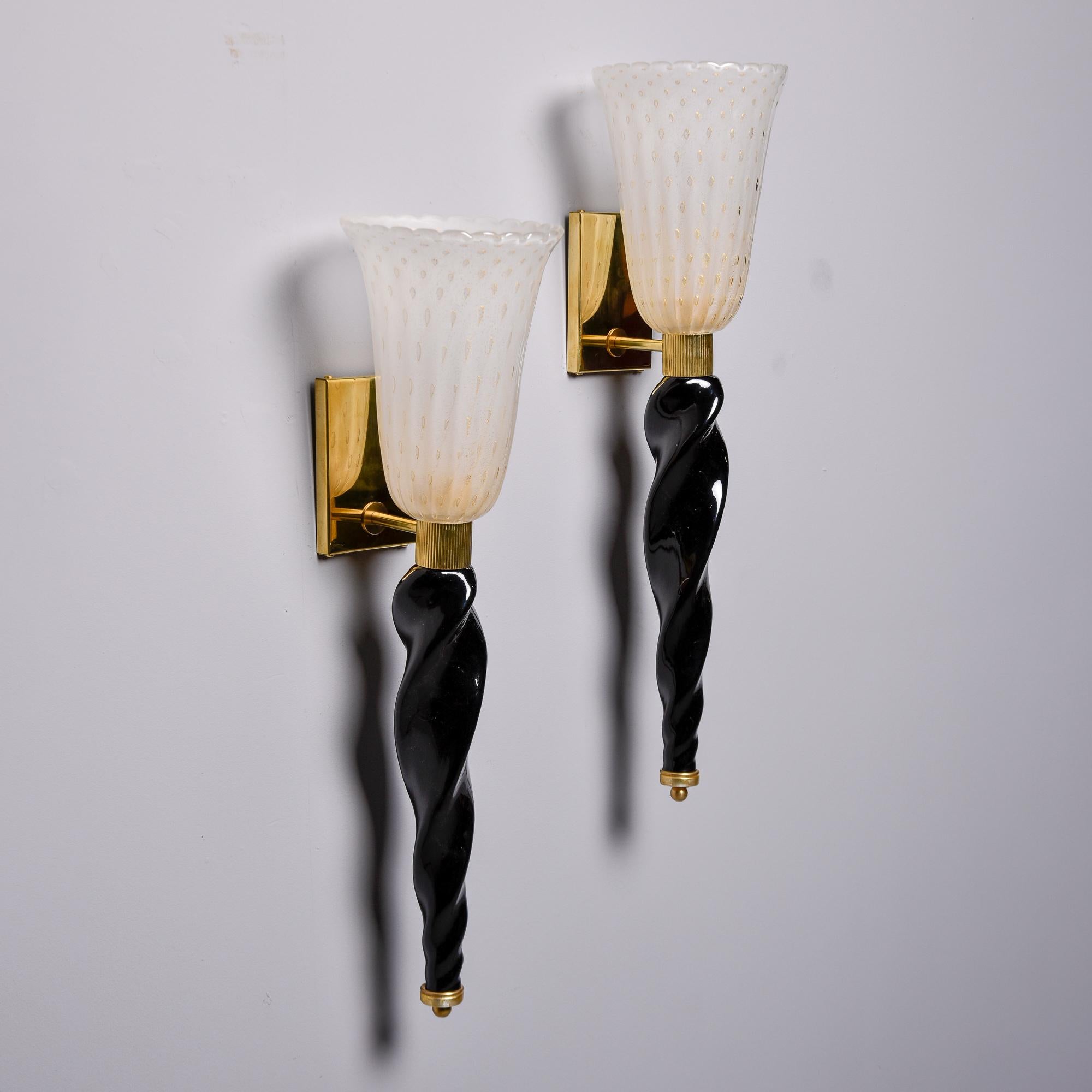 Ces appliques de style torchère sont neuves et fabriquées en Italie en verre de Murano. La générosité de l'échelle donne aux éléments de style classique un peu d'éclat. Les embouts surdimensionnés en verre noir torsadé sont rehaussés d'une bande de