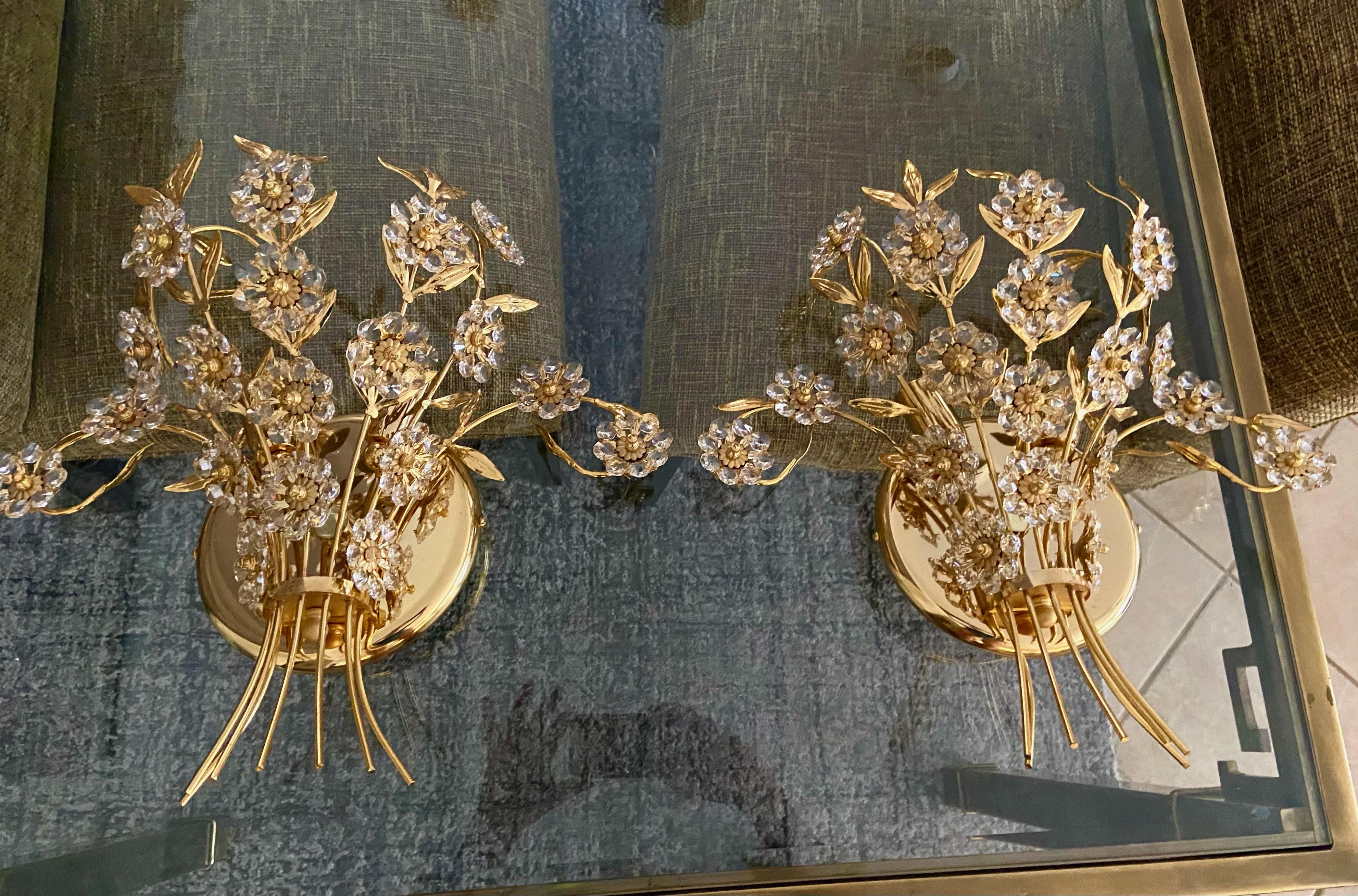 Pair of large scale crystal and gold plated metal floral motif 2-light wall sconces attributed to Palwa, Germany. Each sconces uses two candelabras base bulb. Newly wired.