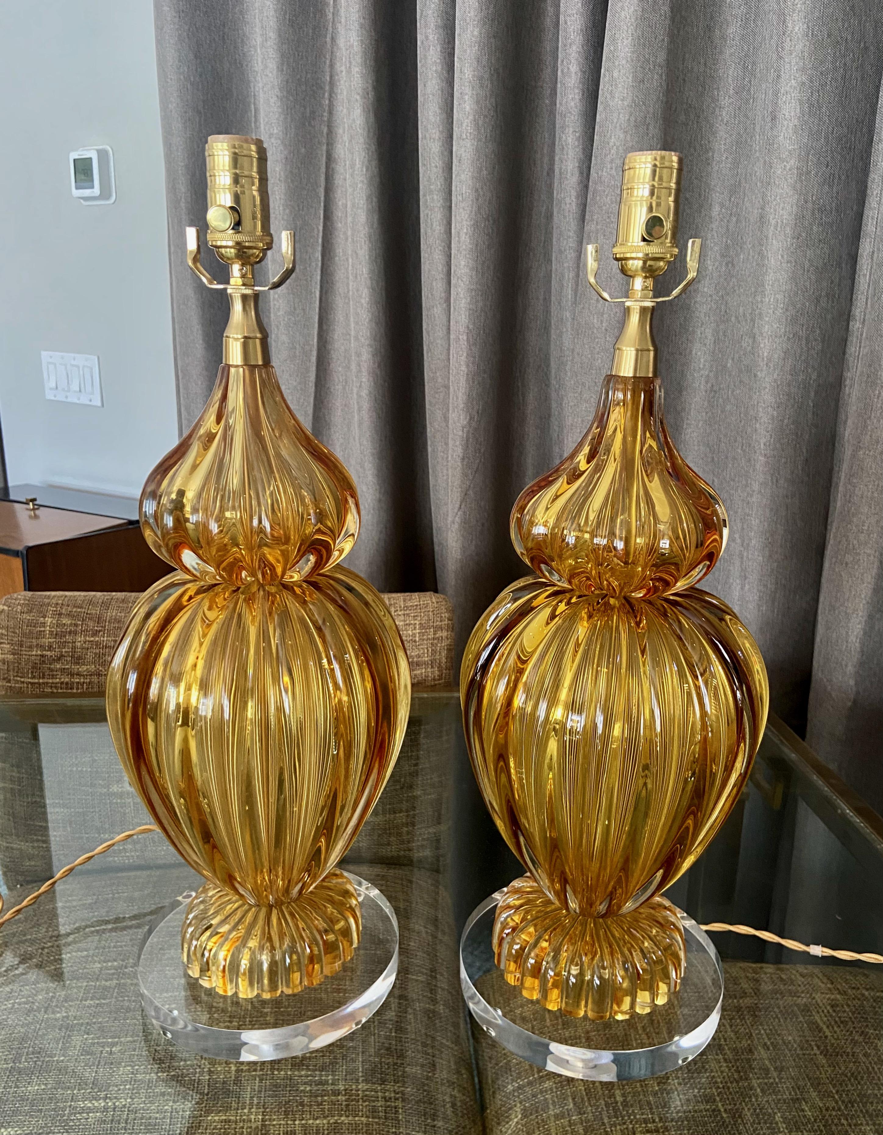 Pair of Seguso Italian Murano handblown amber ribbed glass table lamps. Glass has a rich golden amber color with each lamp weighs over 14 pounds. 
mounted on newer custom acrylic bases. Each newly wired, including new 3 way brass sockets and french