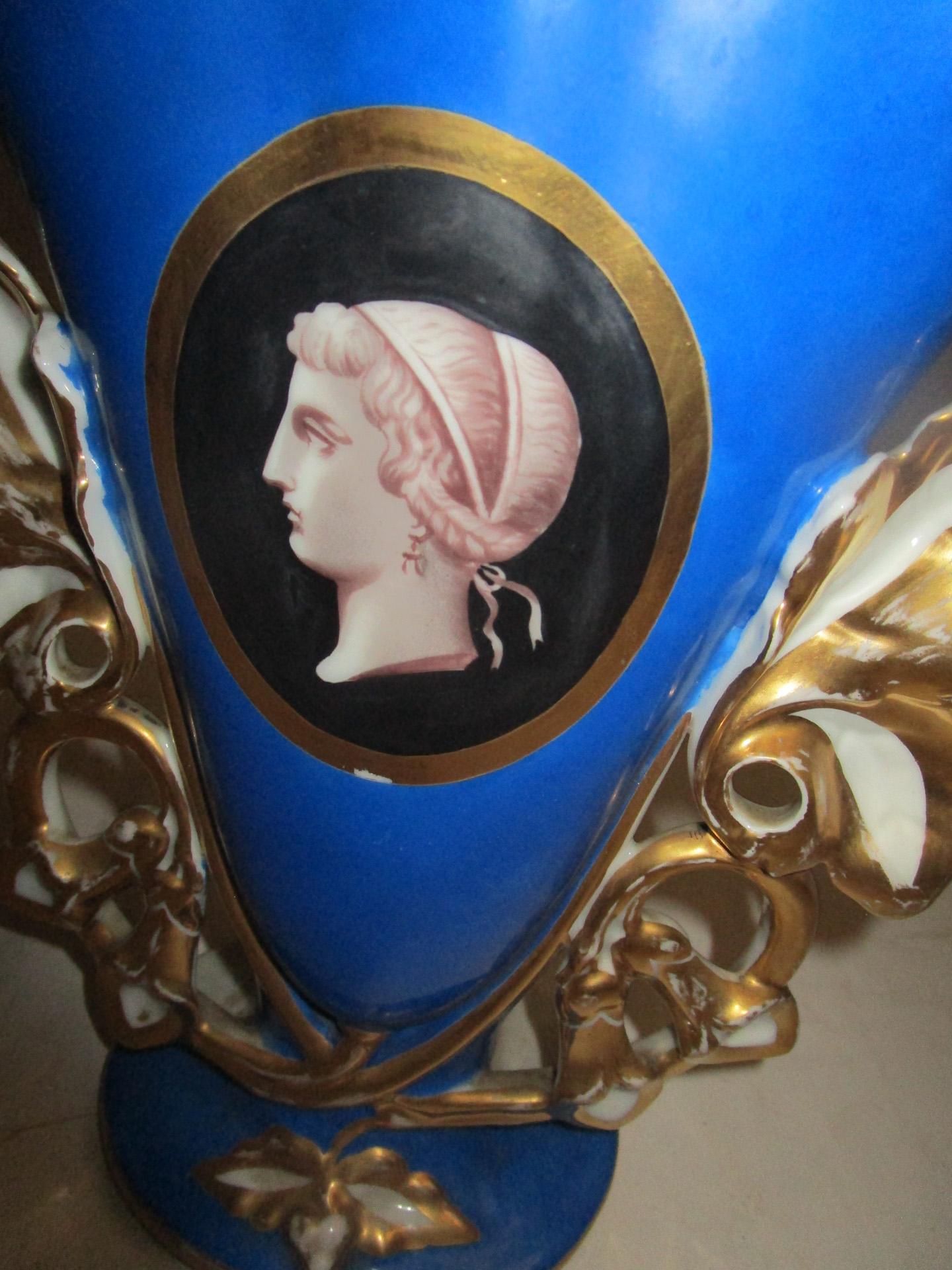 Cette paire de vases de cheminée français bleu cobalt du Vieux Paris présente des médaillons centraux avec des profils grecs classiques encadrés dans un fond noir contrastant. Des reflets dorés soulignent les médaillons ainsi que les sommets