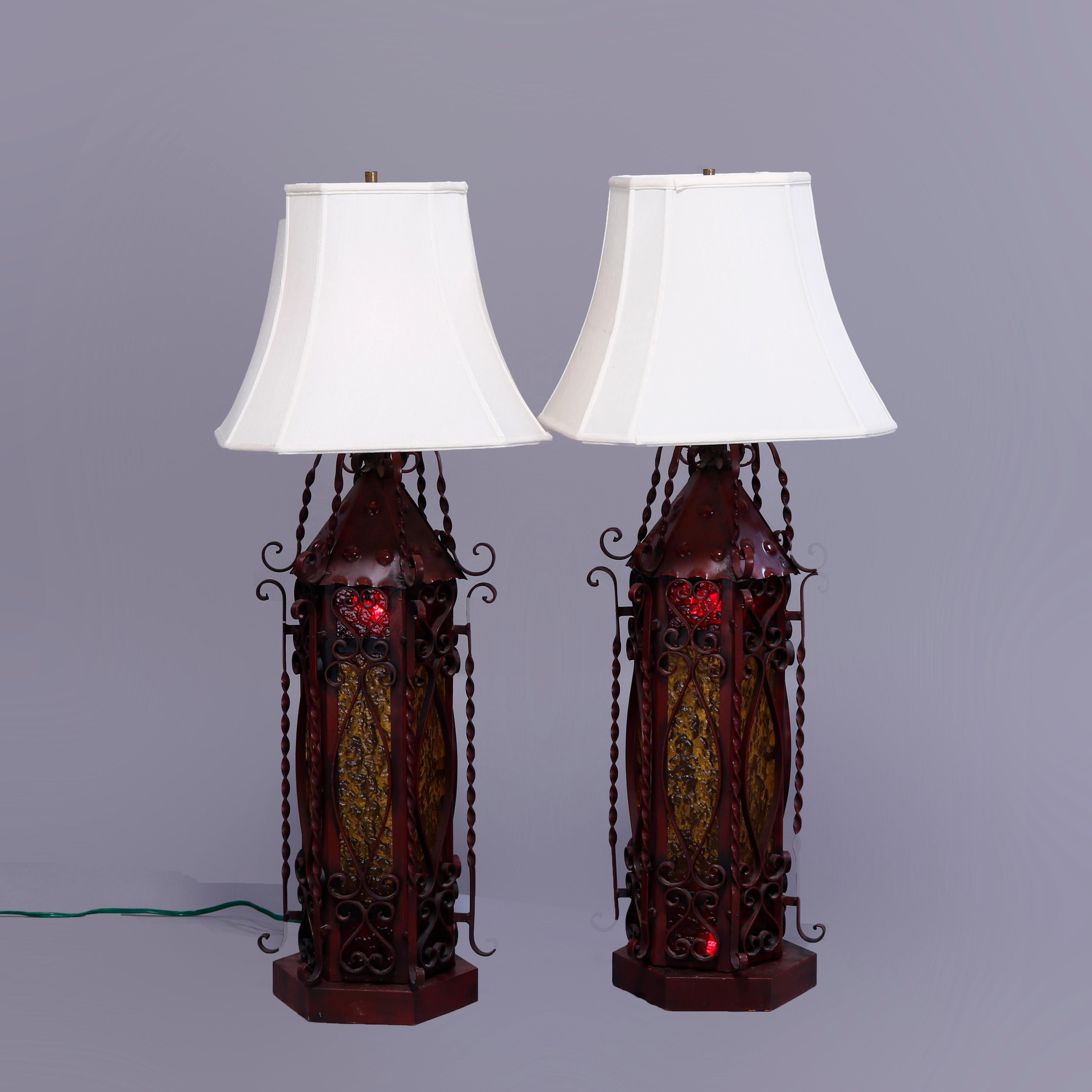 A pair of Spanish style table lamps offer single socket lantern form bases with amber glass in red painted and twisted wrought Iron faceted frames having scroll elements, 20th century

Measures - 43.25''H x 18''W x 18''D.