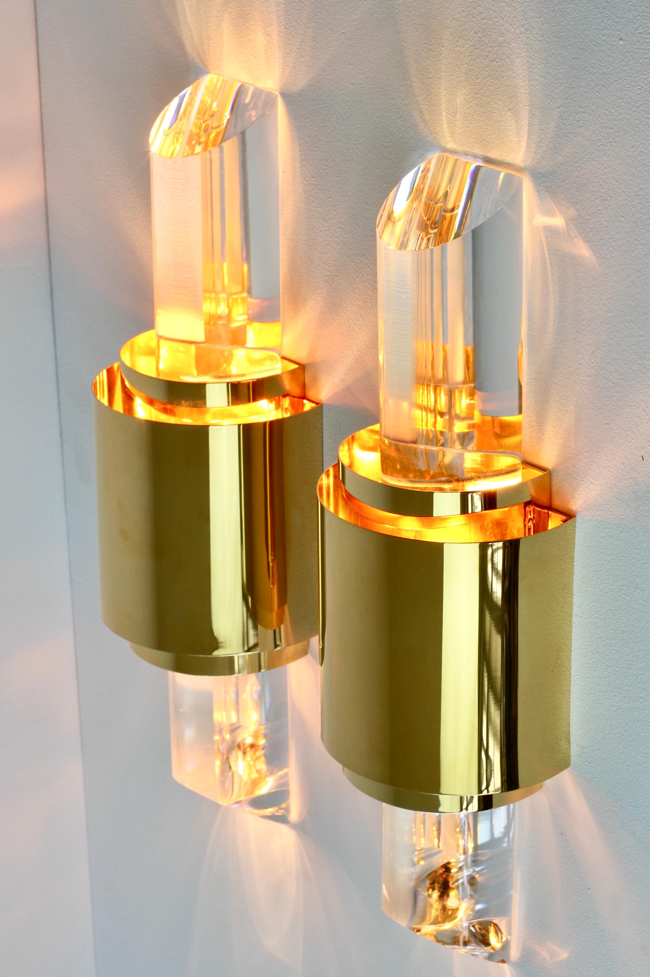 Pair of Hollywood Regency style large, cut / angled acrylic / Lucite wall-mounted lamps, lights or sconces in the style of Karl Springer and made in the latter part of the mid-20th century, circa 1975-1985. These illuminate beautifully as the light