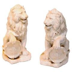 Paire de grandes figurines en céramique émaillée blanche représentant des lions d'entrée avec patte levée sur un bouclier